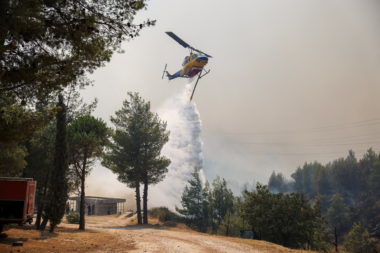 A firefighting helicopter makes a water drop as a wildfire burns in Penteli, near Athens, Greece, August 12, 2024. REUTERS