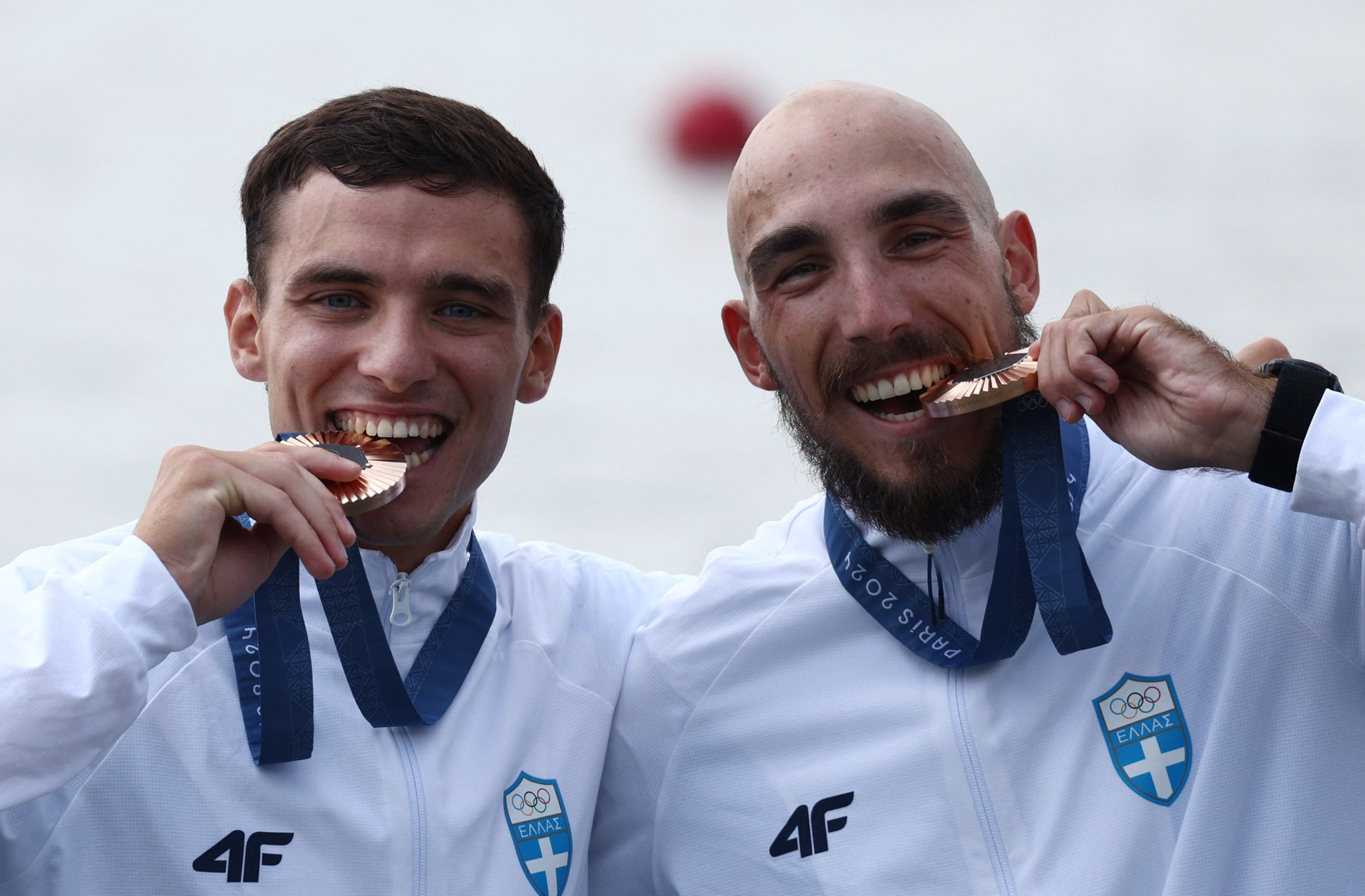 Paris 2024 Olympics - Rowing - LWT Men's Double Sculls Victory Ceremony - Vaires-sur-Marne Nautical Stadium - Flatwater, Vaires-sur-Marne, France - August 02, 2024. Bronze medallists Petros Gkaidatzis of Greece and Antonios Papakonstantinou of Greece bite their medals. REUTERS