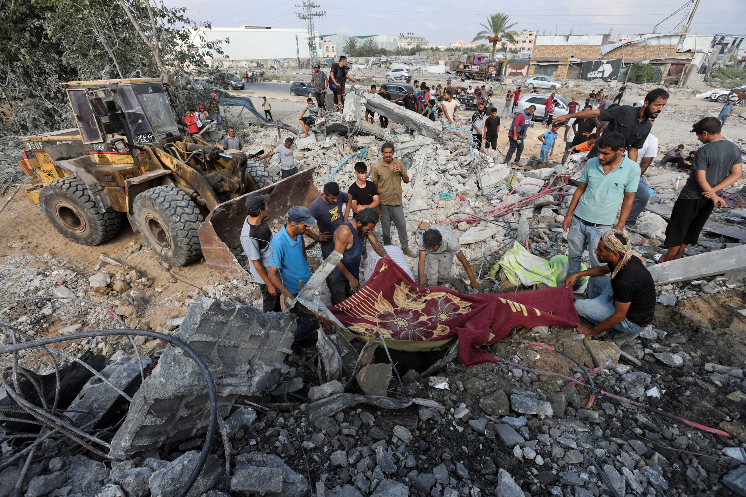 Palestinians stand at the site of an Israeli airstrike on a shelter housing displaced people, amid the conflict between Israel and Hamas, in central Gaza Strip, August 17, 2024. REUTERS
