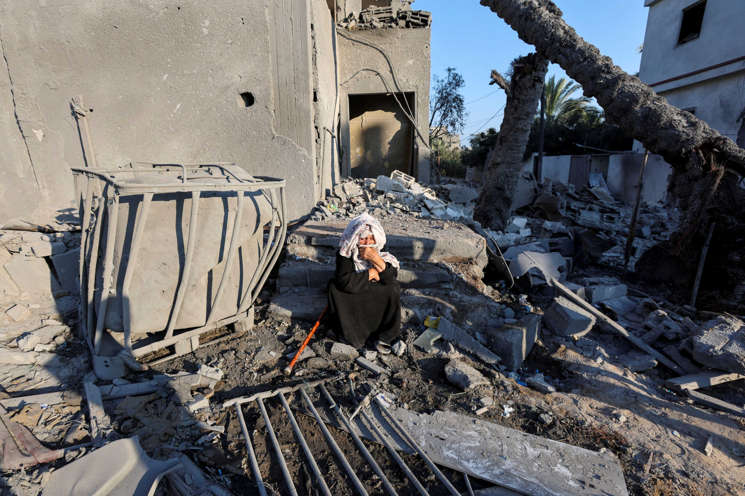 A Palestinian woman sits at the site an Israeli strike on a house, amid the Israel-Hamas conflict, in Deir Al-Balah in the central Gaza Strip, August 7, 2024. REUTERS
