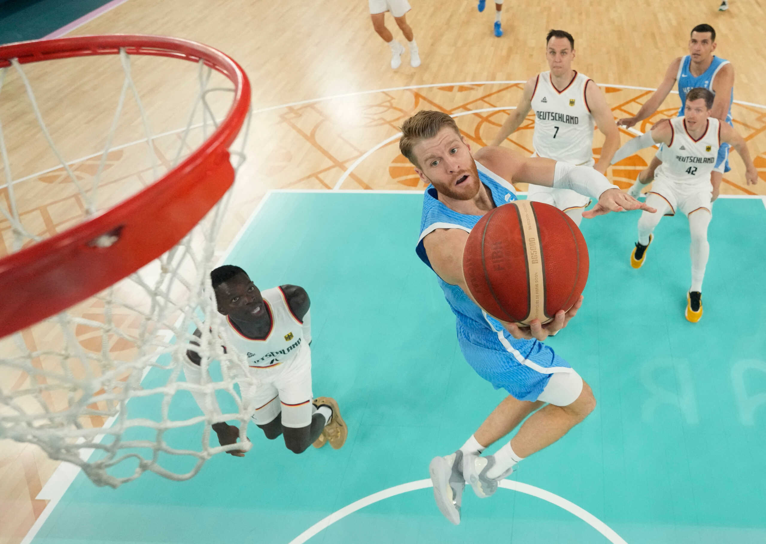 Paris 2024 Olympics - Basketball - Men's Quarterfinal- Germany vs Greece - Bercy Arena, Paris, France - August 06, 2024. Thomas Walkup of Greece scores a basket past Dennis Schroder of Germany Pool via REUTERS