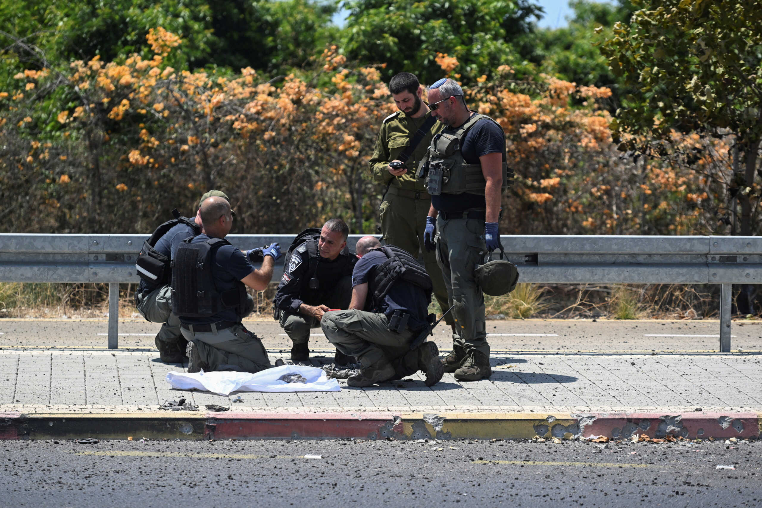 Israeli police and a soldier work at the impact site of a projectile, after Lebanon's armed group Hezbollah said it launched a swarm of attack drones against military targets in northern Israel, in Nahariya, Israel, August 6, 2024. REUTERS