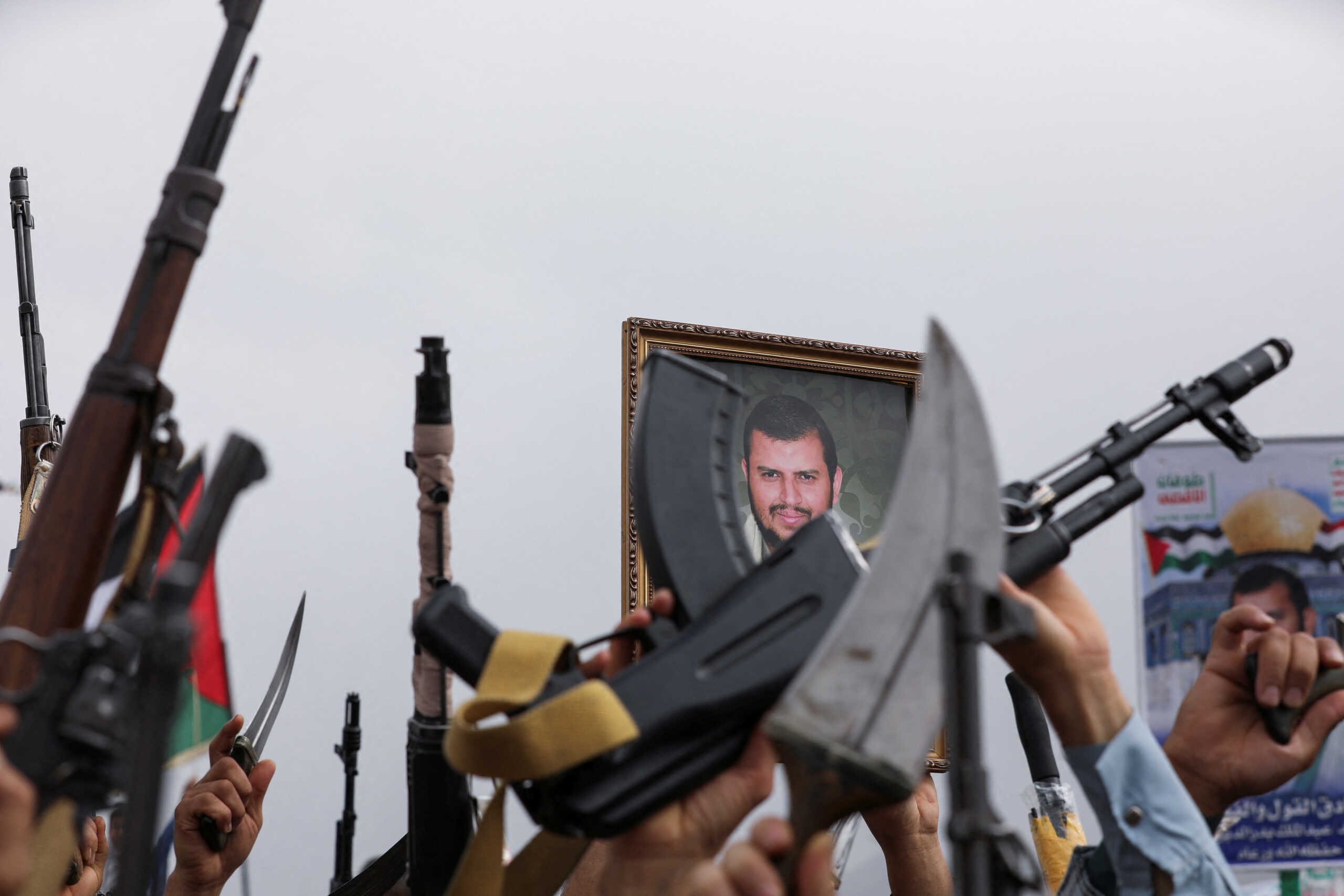 A poster of Houthi leader, Abdul Malik al-Houthi, is held by a protester as others hold up their weapons during a rally held to show support to Palestinians in the Gaza Strip, amid Israel-Hamas conflict, in Sanaa, Yemen July 26, 2024. REUTERS