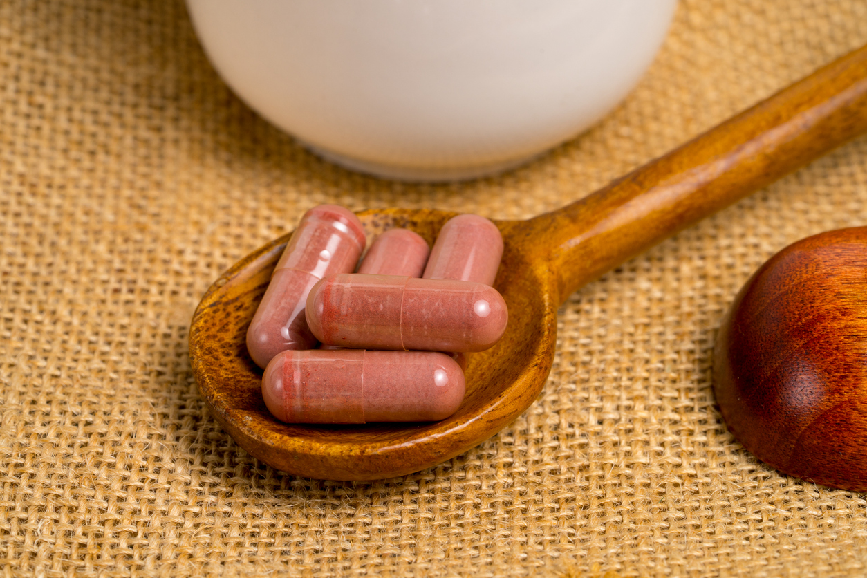 Red yeast rice or angkak or kojic rice supplemet capsule on wooden spoon