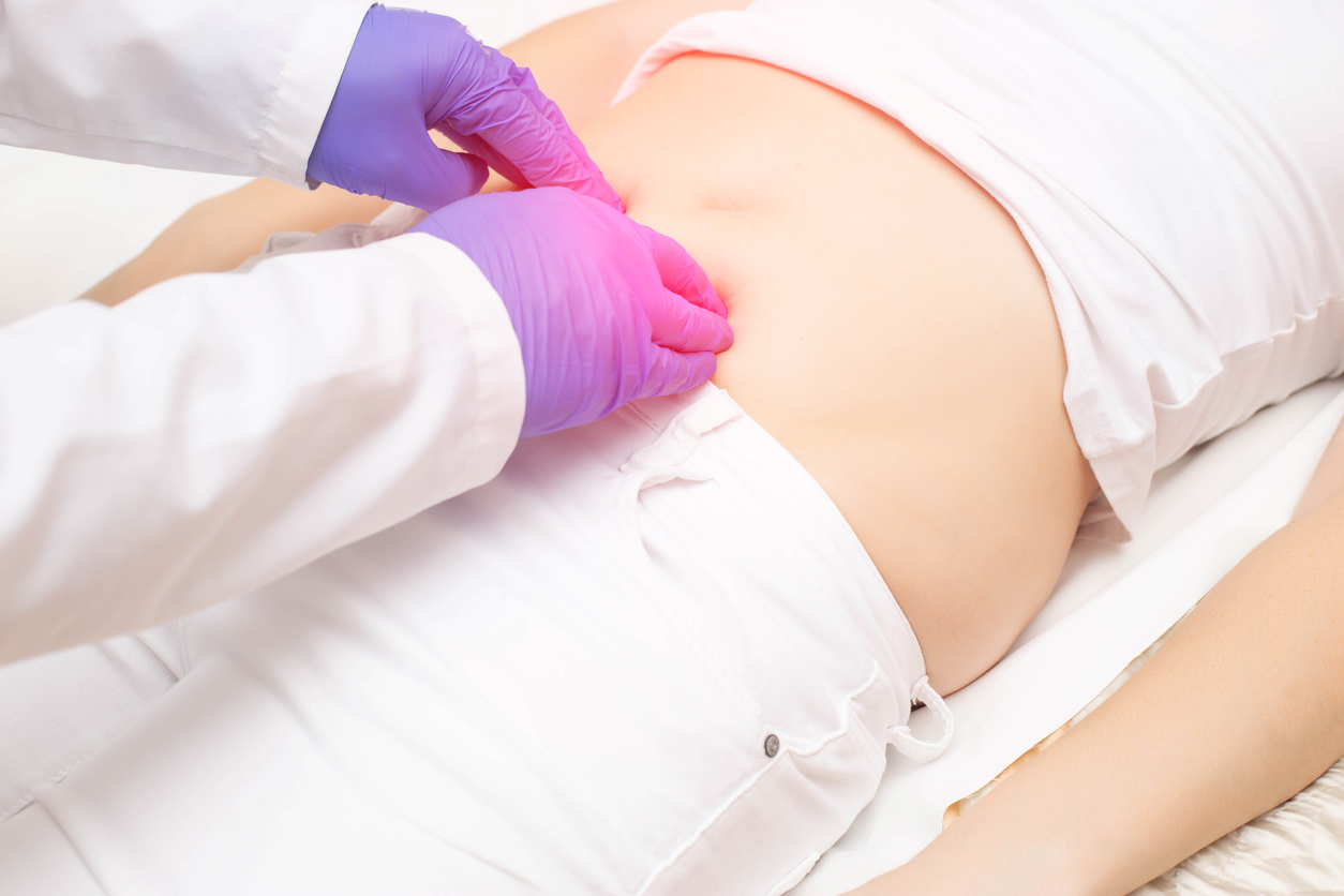 The doctor probes the lower abdomen in a girl who has pain and inflammation of the bladder. The concept of diseases in girls cystitis, kidney stones