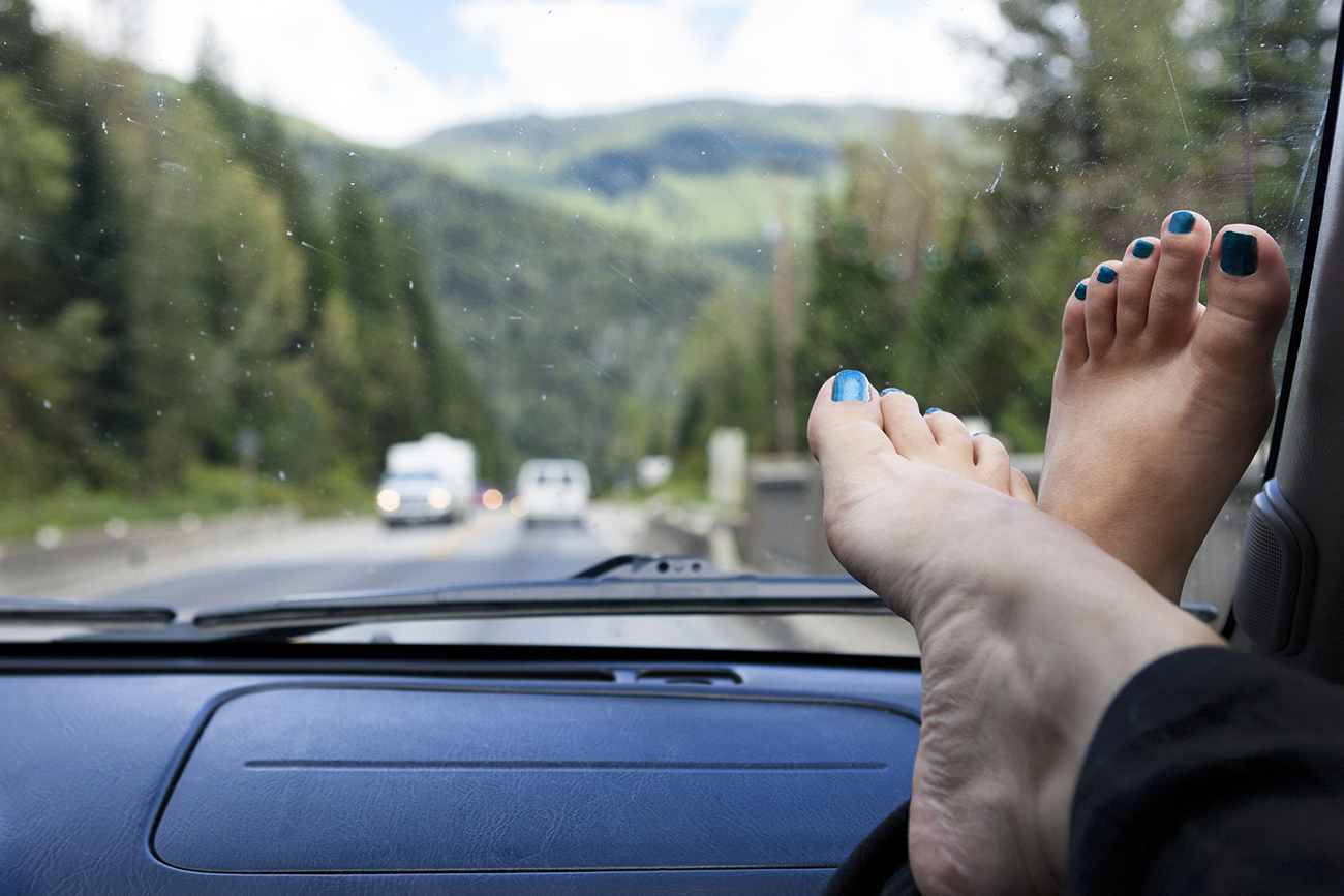 Feet up on the dashboard during a road trip through the mountains of the Canadian Rockies in Yoho National Park, British Columbia, Canada.