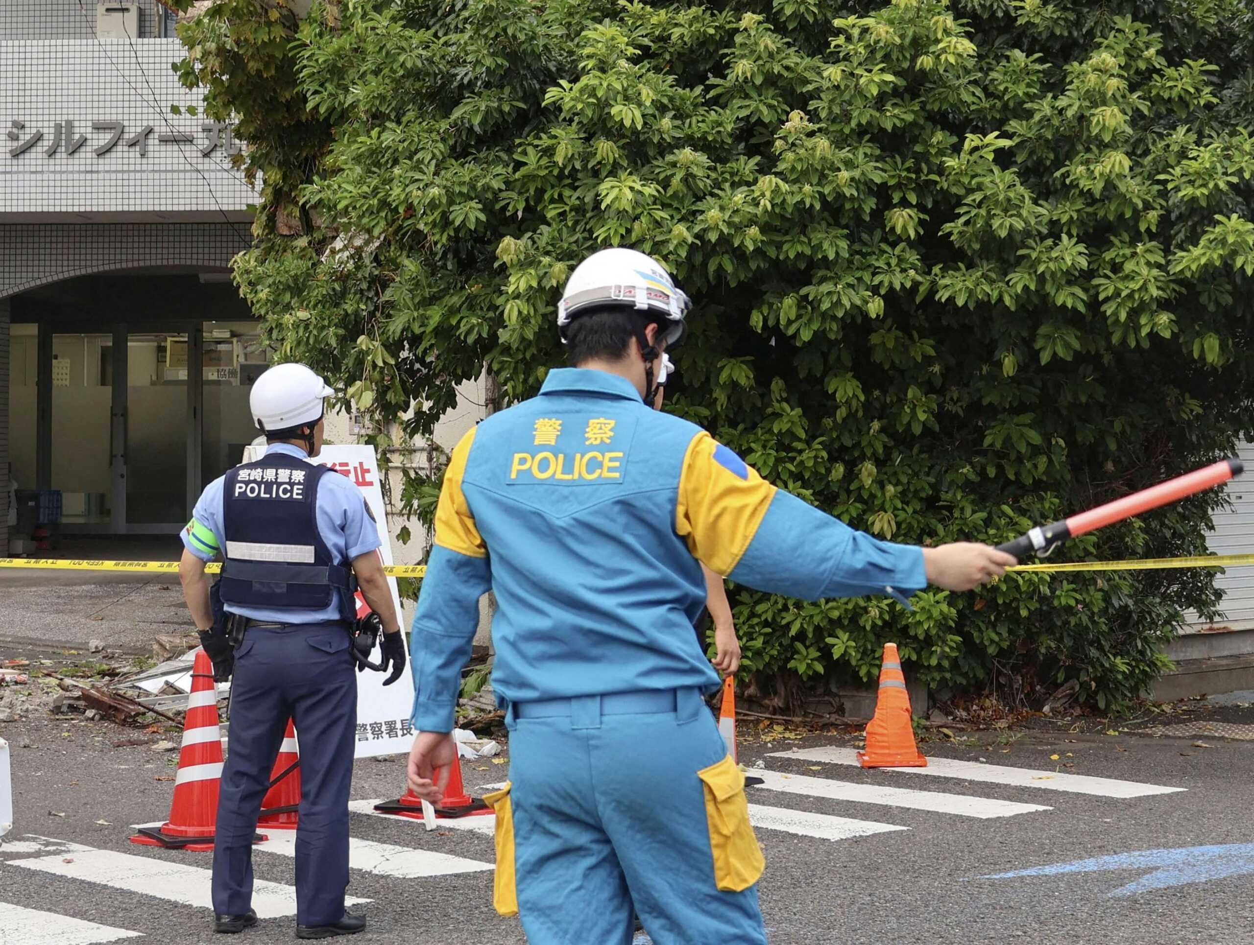 Police officers stand guard near a building damaged following an earthquake in Miyazaki, southwestern Japan, August 8, 2024, in this photo taken by Kyodo. Mandatory credit Kyodo