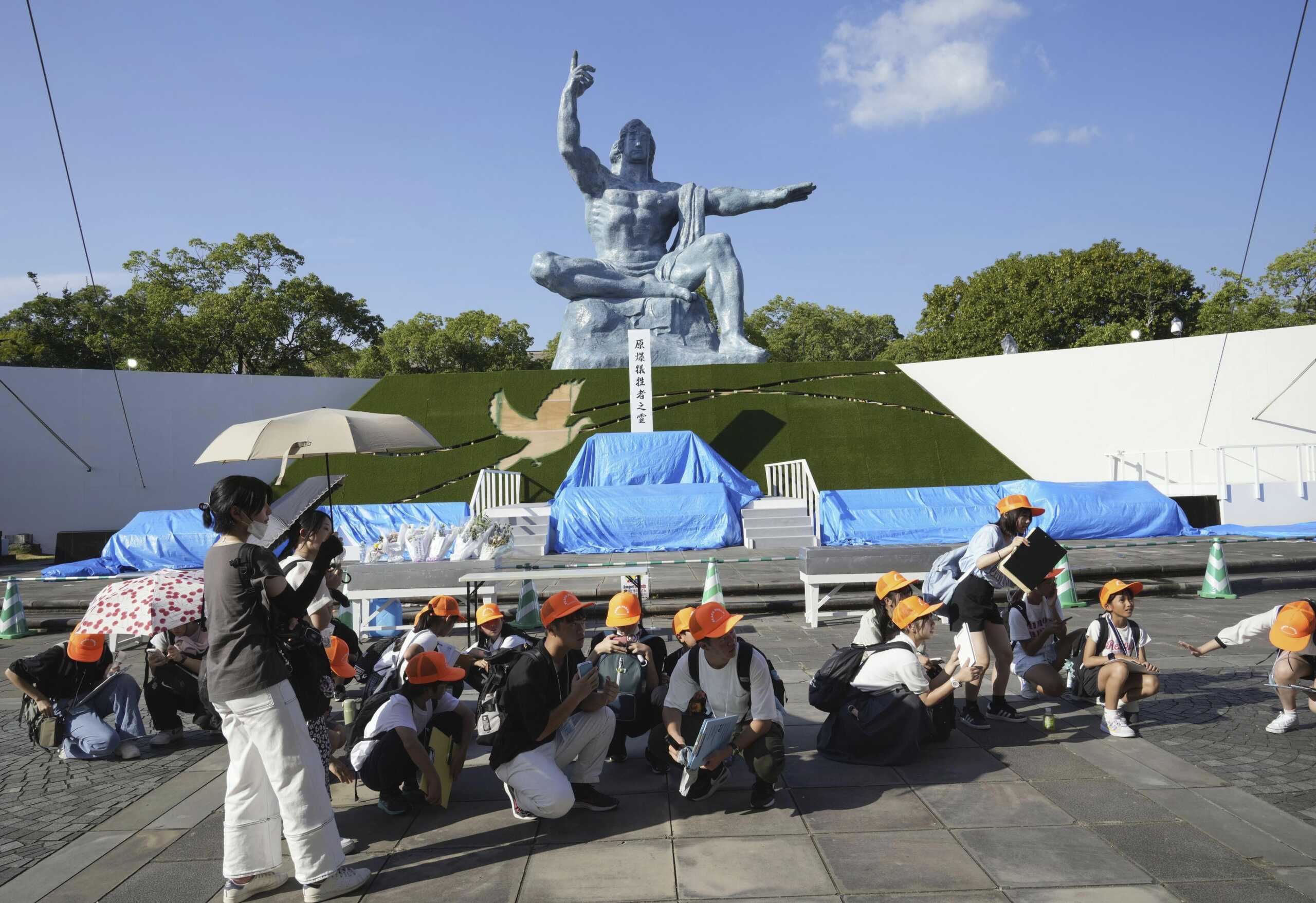Visitors to the Peace Park crouch as an earthquake alert was issued in Nagasaki, western Japan, Thursday, Aug. 8, 2024.(Kyodo News via AP)