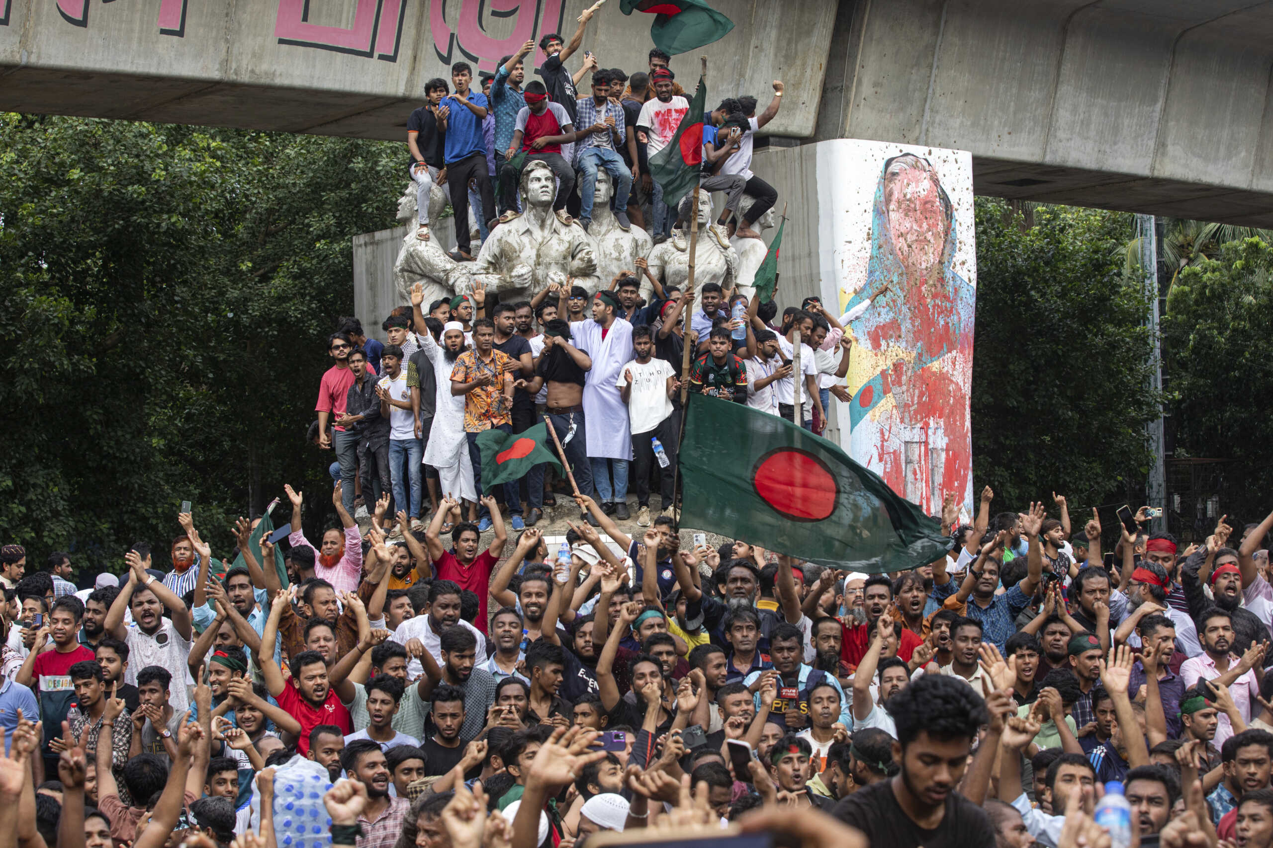 Protesters climb a public monument as they celebrate after getting the news of Prime Minister Sheikh Hasina's resignation, in Dhaka, Bangladesh, Monday, Aug. 5, 2024. (AP Photo