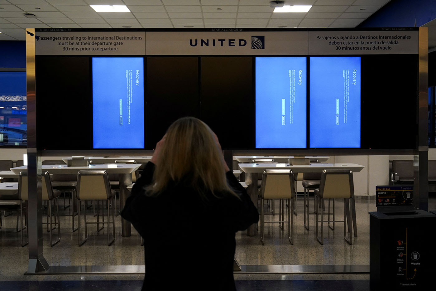 A traveler uses her mobile phone to photograph a departures board displaying blue error screens, also known as the "Blue Screen of Death" inside Terminal C in Newark International Airport, after United Airlines and other airlines grounded flights due to a worldwide tech outage caused by an update to Crowdstrike's "Falcon Sensor" software which crashed Microsoft Windows systems, in Newark, New Jersey, U.S., July 19, 2024. REUTERS