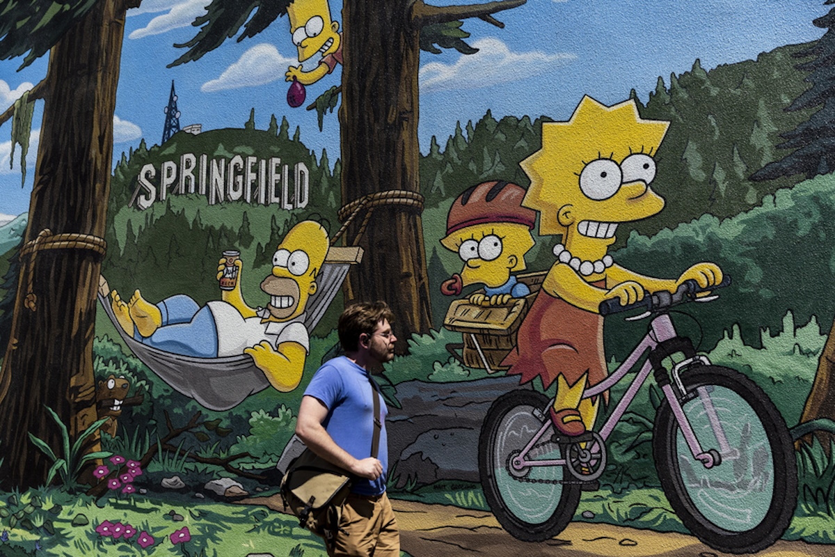 epa10090351 A pedestrian walks by a mural by Old City Artists showing The Simpsons family in Springfield, Oregon, USA, 24 July 2022.  EPA