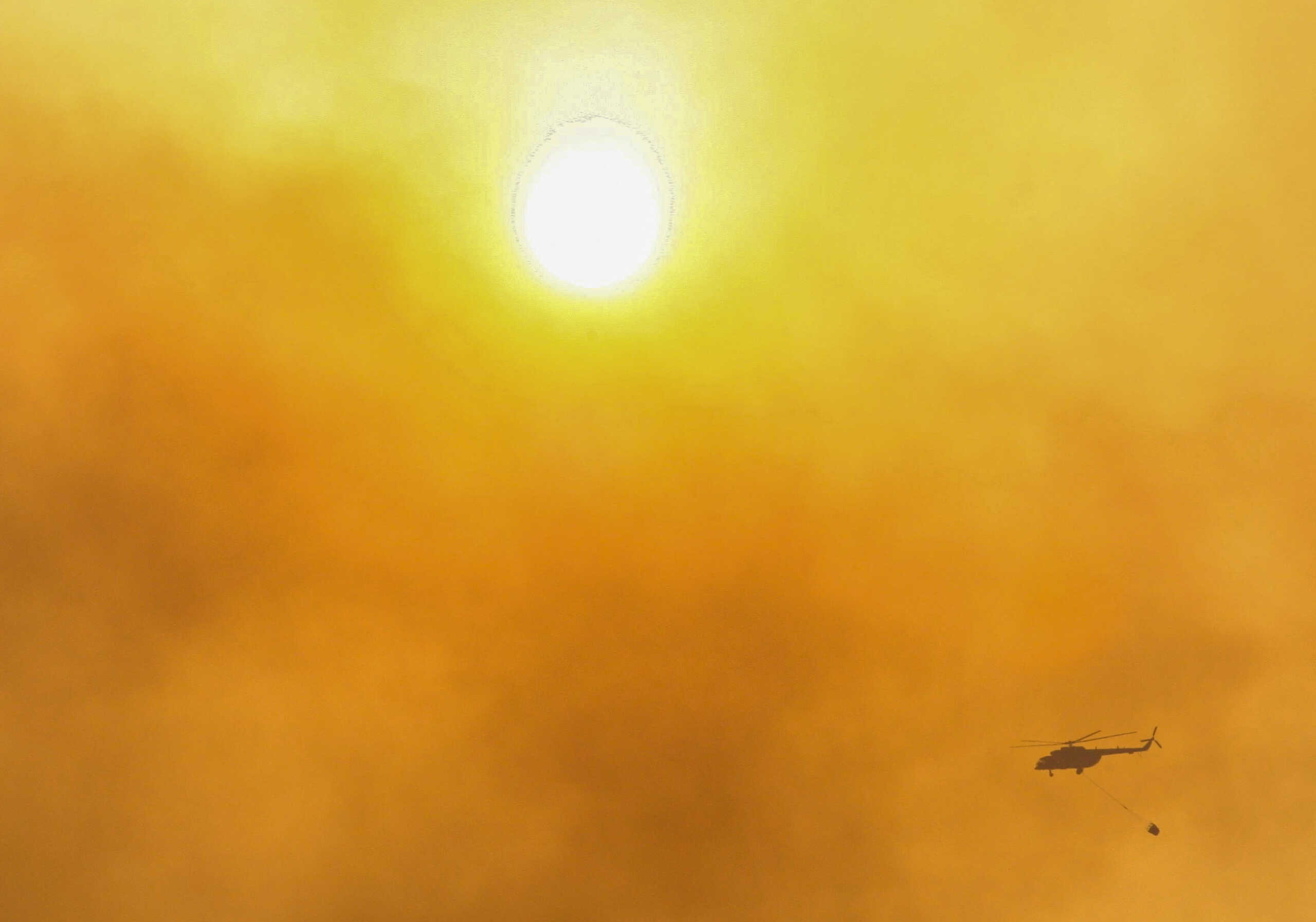 FILE PHOTO: A firefighting helicopter flies through the smoke that raises from wildfires during a sunset near Marmaris, a town in Mugla province, Turkey, June 23, 2022. REUTERS