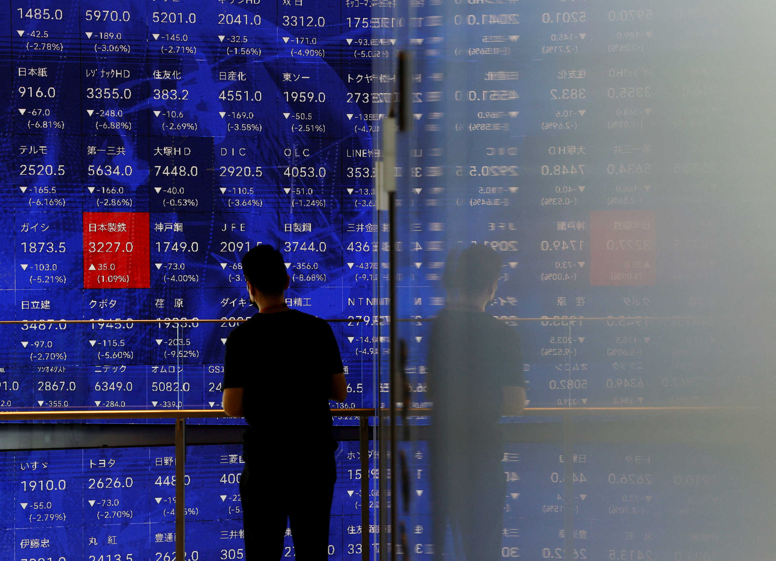 A man stands next to an electronic stock quotation board inside a building in Tokyo, Japan August 2, 2024. REUTERS