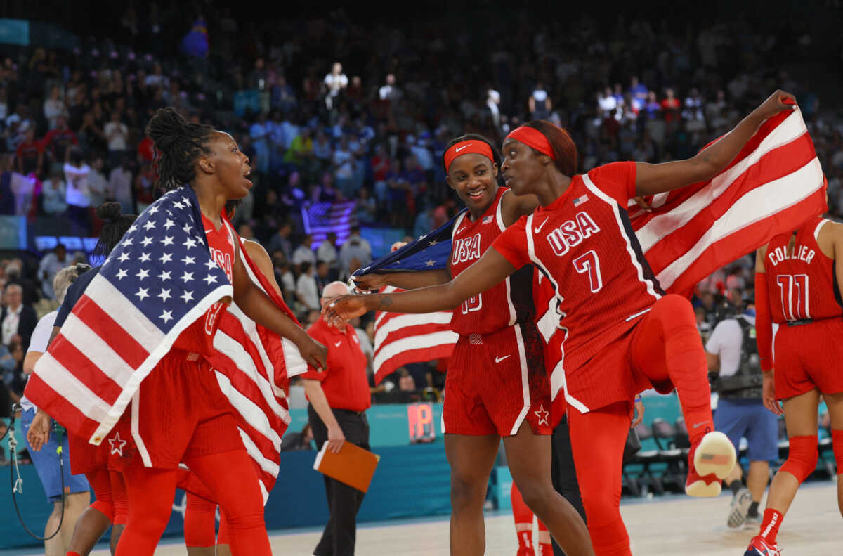 Paris 2024 Olympics - Basketball - Women's Gold Medal Game - France vs United States - Bercy Arena, Paris, France - August 11, 2024. Chelsea Gray of United States, Kahleah Copper of United States and Jackie Young of United States celebrate with flags after United States win gold. REUTERS