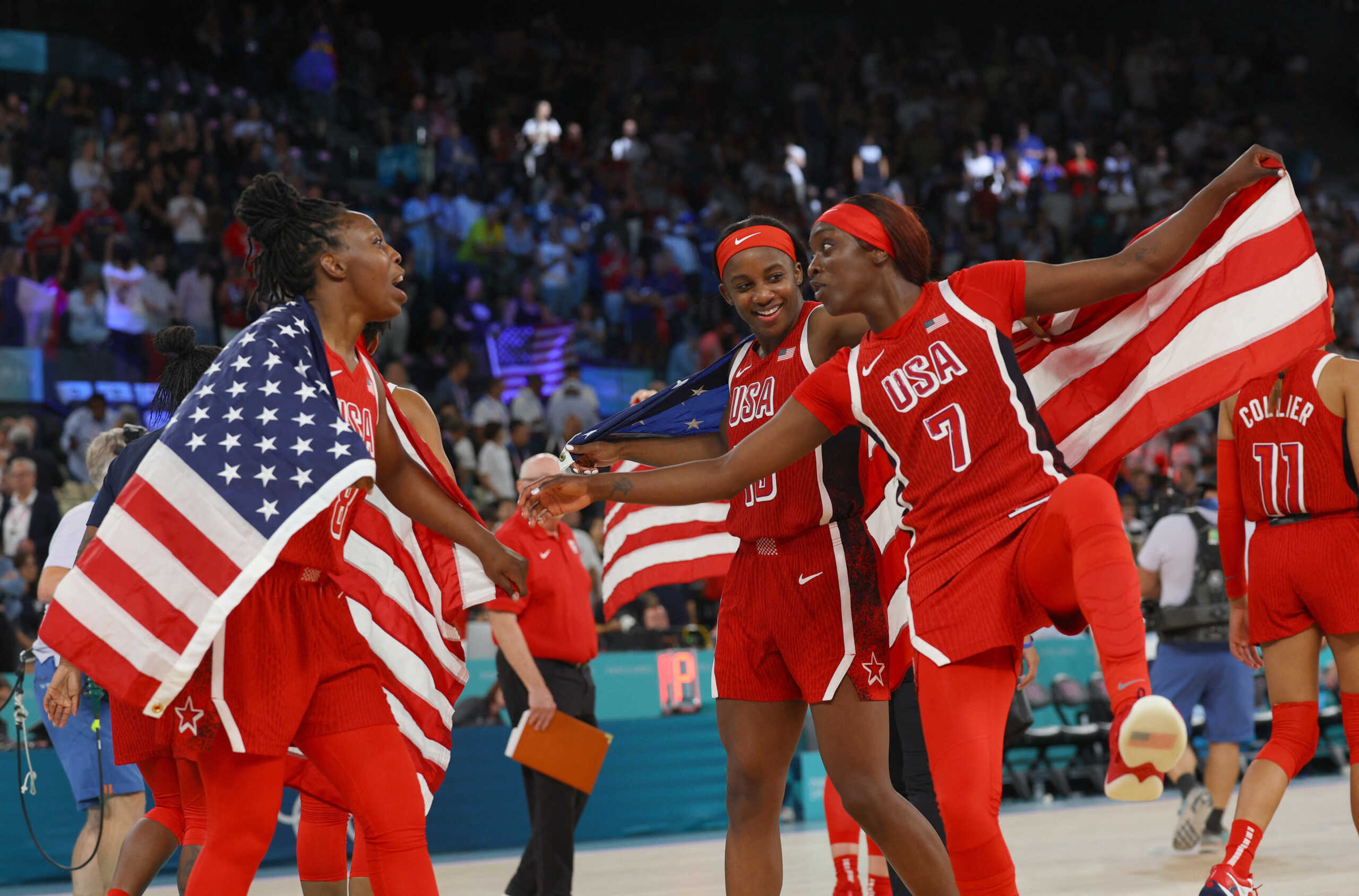 Paris 2024 Olympics - Basketball - Women's Gold Medal Game - France vs United States - Bercy Arena, Paris, France - August 11, 2024. Chelsea Gray of United States, Kahleah Copper of United States and Jackie Young of United States celebrate with flags after United States win gold. REUTERS