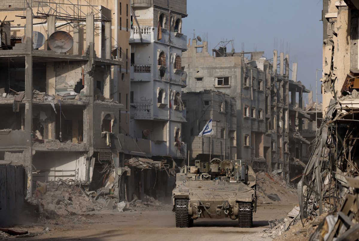An armoured vehicle drives as damaged buildings are seen in the background, amid the ongoing ground operation of the Israeli army against Palestinian Islamist group Hamas, in the Gaza Strip, September 13, 2024. REUTERS