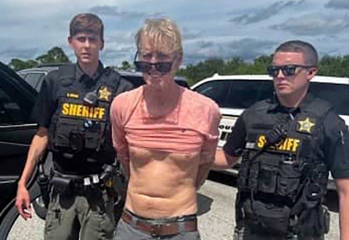 Ryan W. Routh, suspected of attempting to assassinate Republican presidential nominee and former U.S. President Donald Trump at his West Palm Beach golf course, stands handcuffed between two Martin County Sheriff's office deputies after his arrest during a traffic stop near Palm City, Florida, U.S., September 15, 2024.  Martin County Sheriff's Office