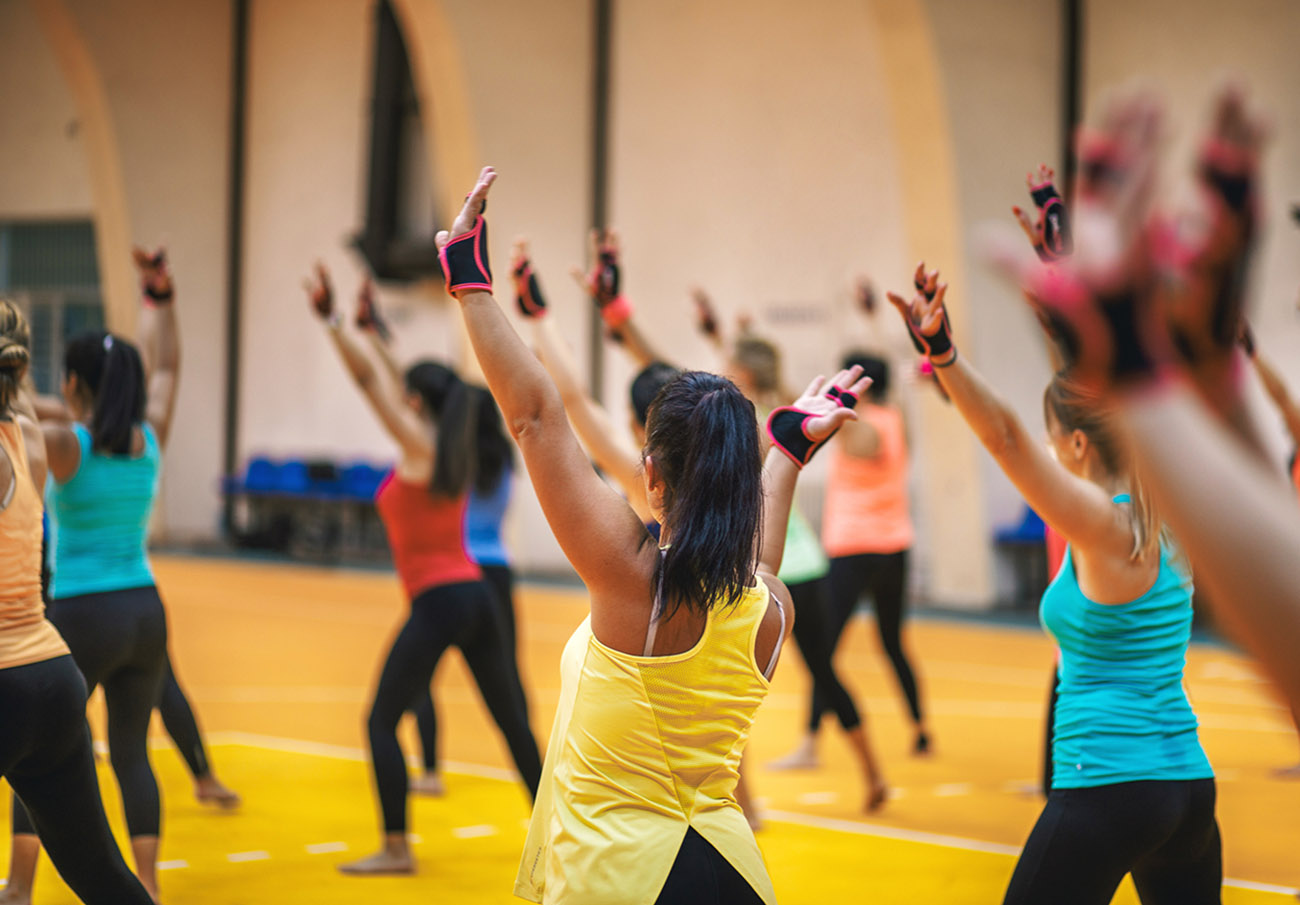 Mixed age group of fitness women, exercising together in a sports hall.