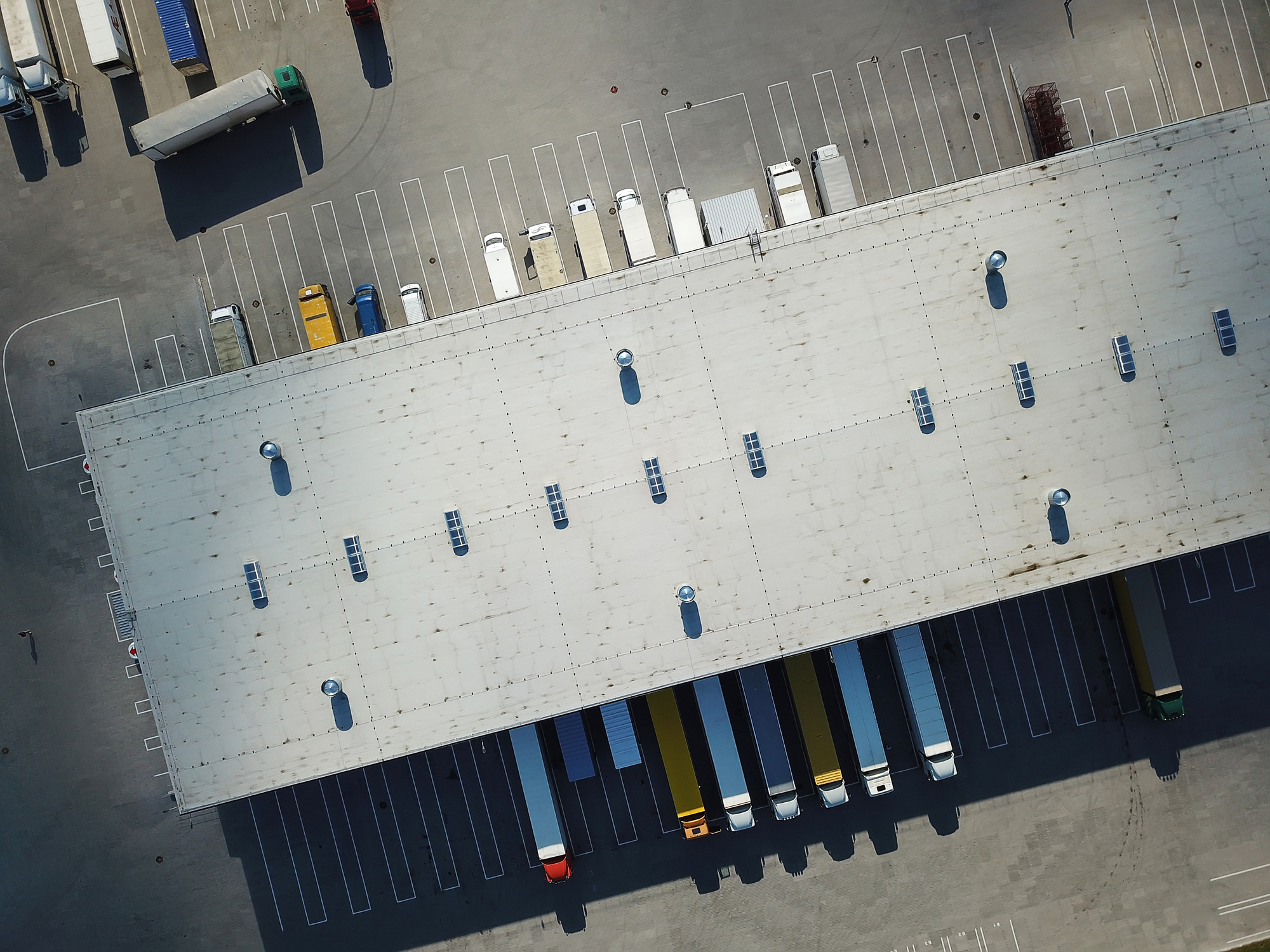 Aerial view of goods warehouse. Logistics center in industrial city zone from above. Aerial view of trucks loading at logistic center