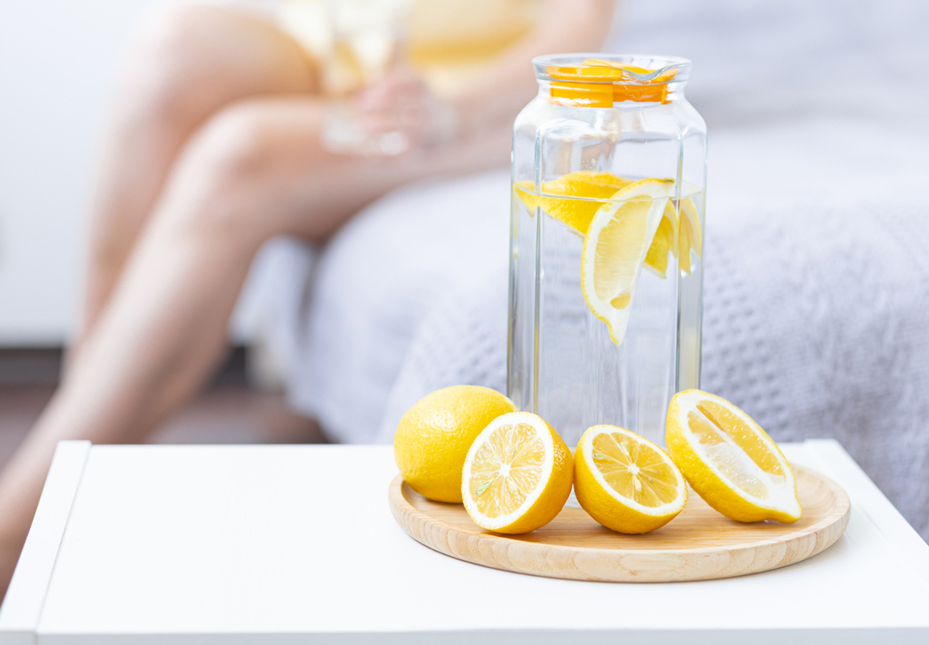 Healthy drink - water with lemon. Female drinking from the glass on background. Concept of clean eating, low calories, weight loss, dieting. Natural organic morning beverage