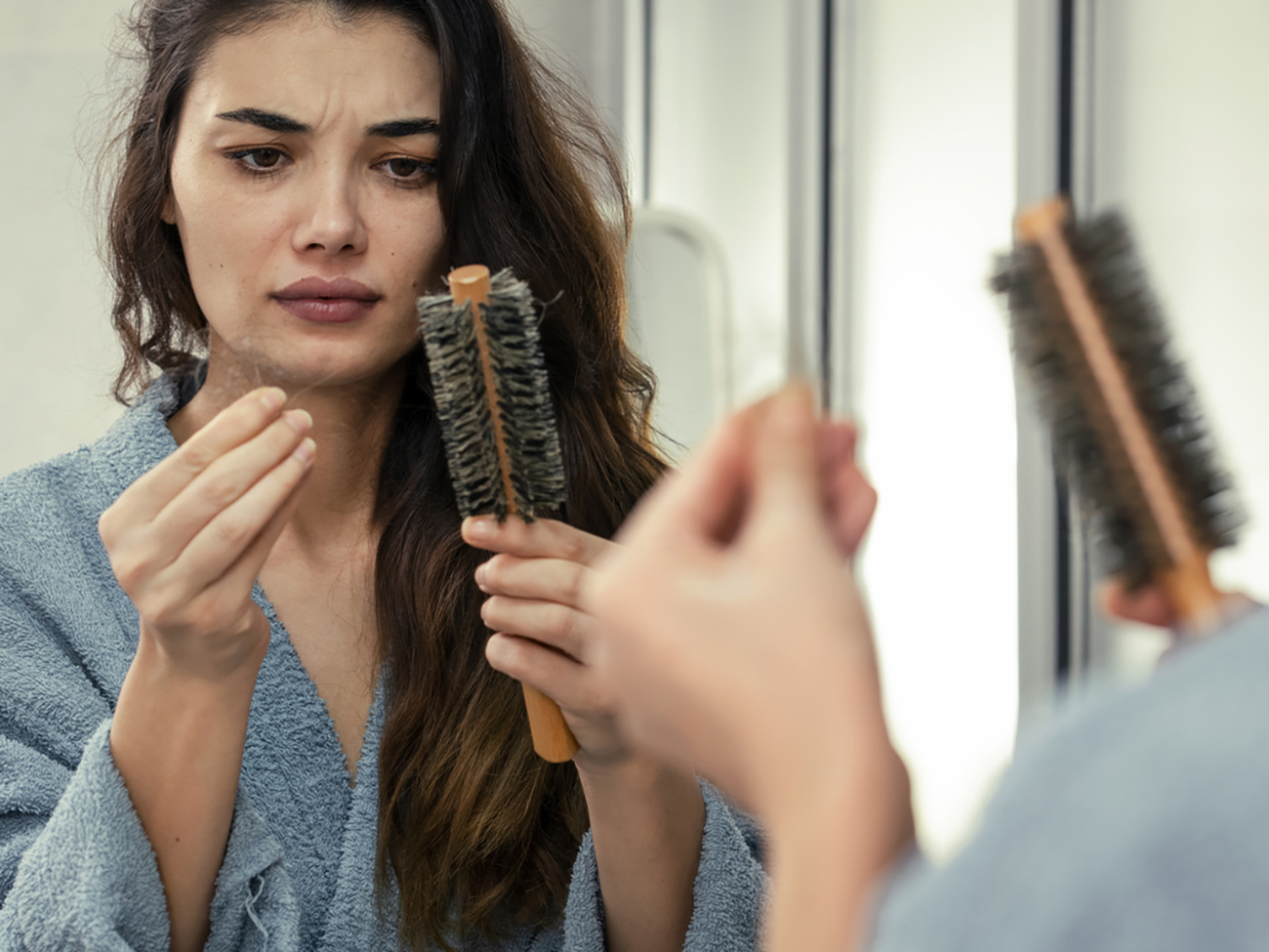 Woman losing hair on hairbrush in hand