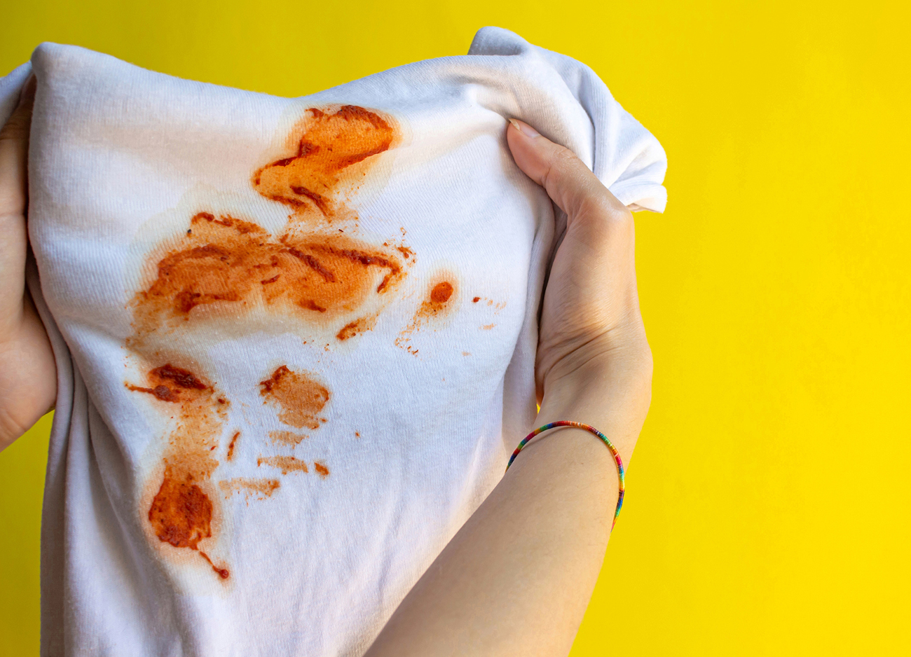 Food stains on white shirt. Hand holding dirty t shirt with copy space.