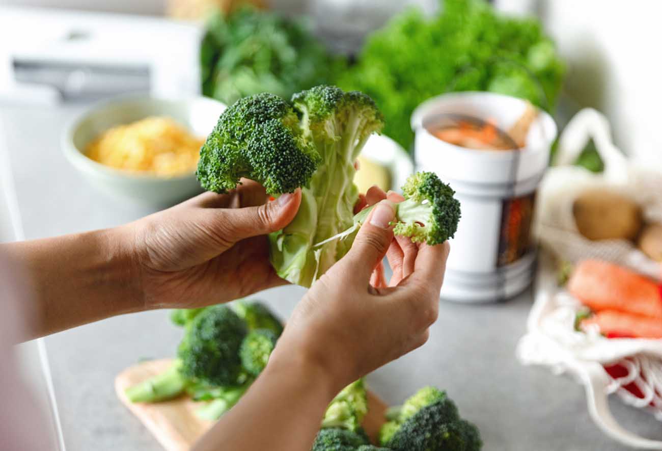 Woman preparing healthy vegetarian food. Cutting vegetables into small pieces.