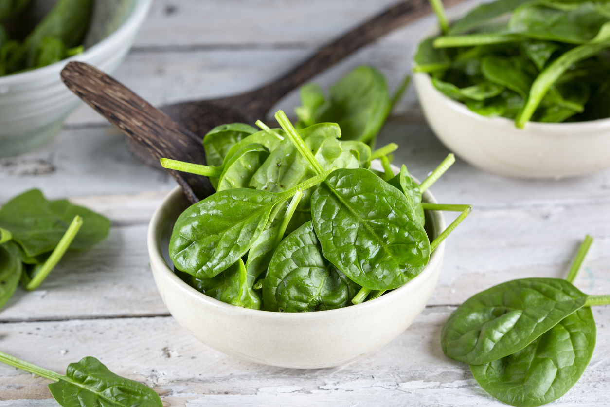 Fresh baby spinach leaves - wooden background