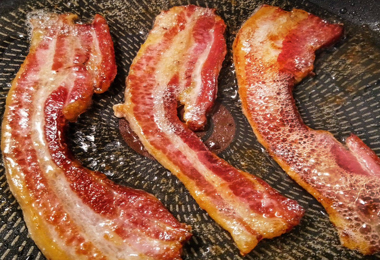 Gourmet juicy, crunchy, sizzling belly bacon strips, fried in non stick frying pan - detail, high resolution stock photography.