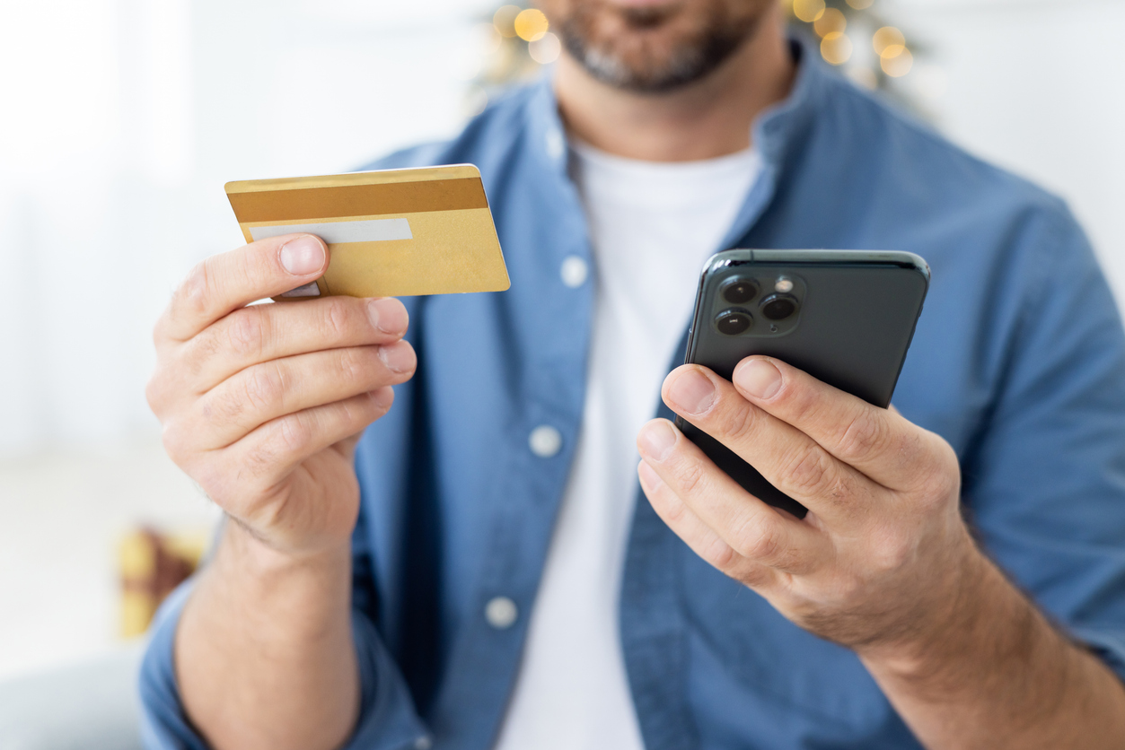 Close-up photo of young male hands holding a credit card and a mobile phone.