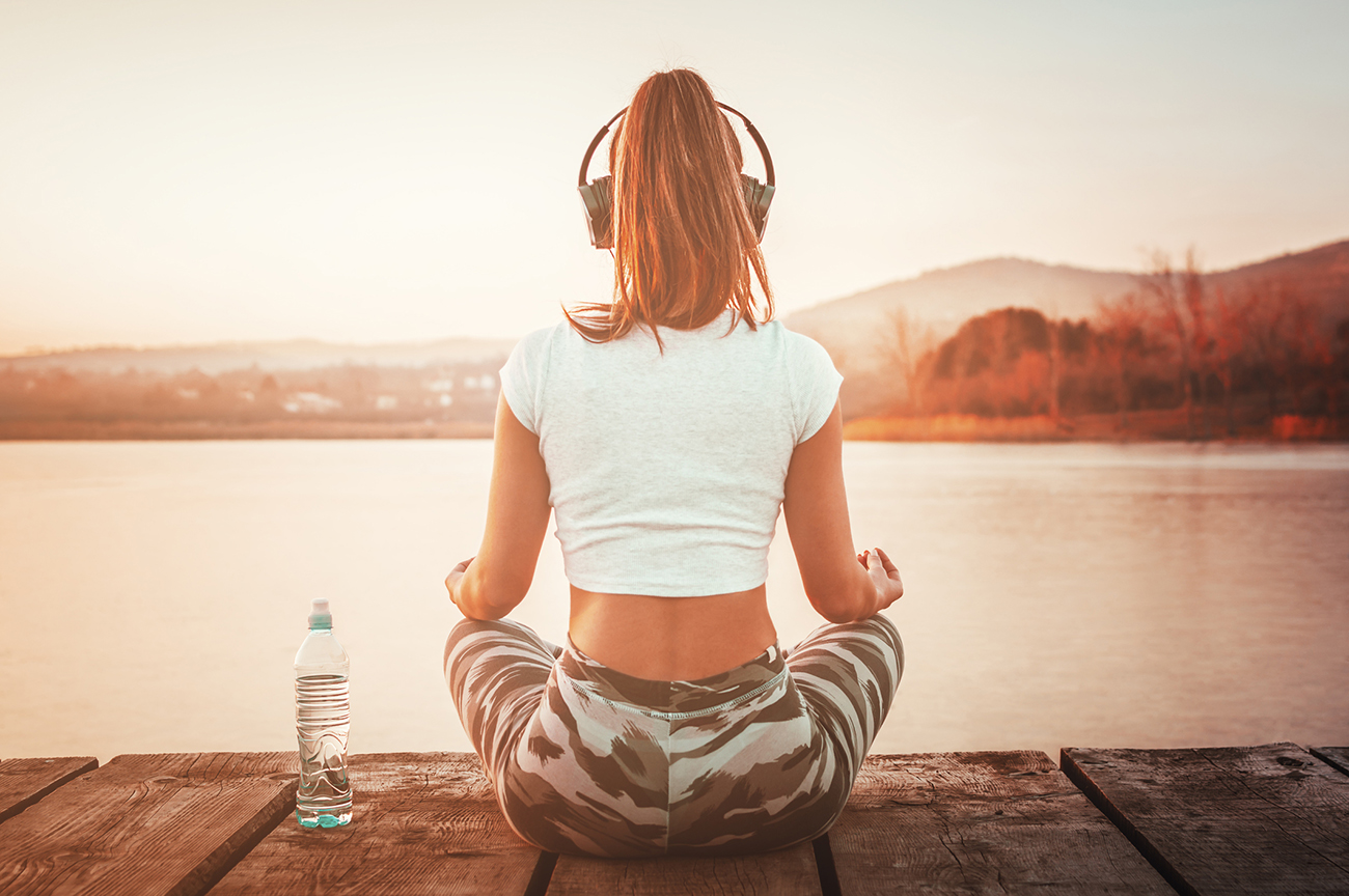 Yoga relaxation concept. Female looking at lake water in nature meditating away from everyday city life