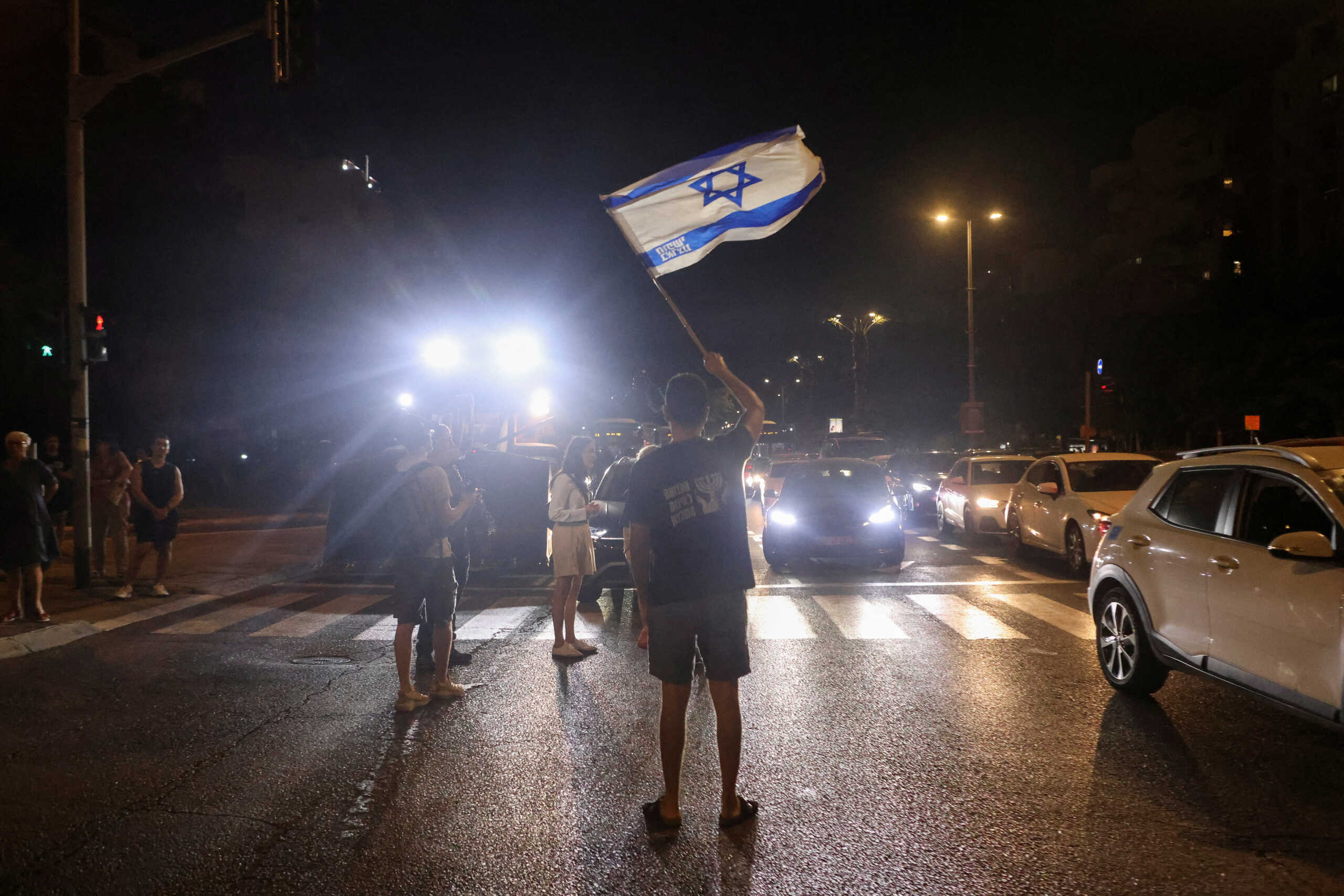 A person waves an Israeli flag on the road as people attend a protest against the government and to show support for the hostages who were kidnapped during the deadly October 7 attack, amid the ongoing conflict in Gaza between Israel and Hamas, in Tel Aviv, Israel September 16, 2024. REUTERS