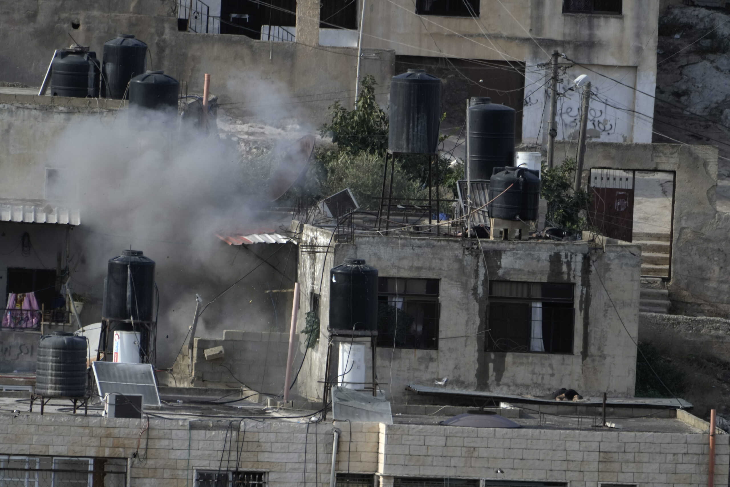 EDS NOTE: GRAPHIC CONTENT - An explosion is seen as three bodies lie motionless on rooftops in the West Bank town of in the West Bank town of Qabatiya during a raid, Thursday, Sept. 19, 2024. (AP Photo