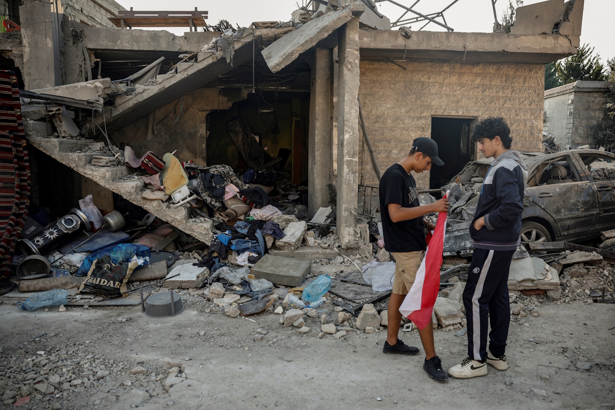 A teenager holds a Lebanese flag next to debris of houses destroyed in an Israeli strike in Maaysrah, north of Beirut, Lebanon, September 27, 2024. REUTERS