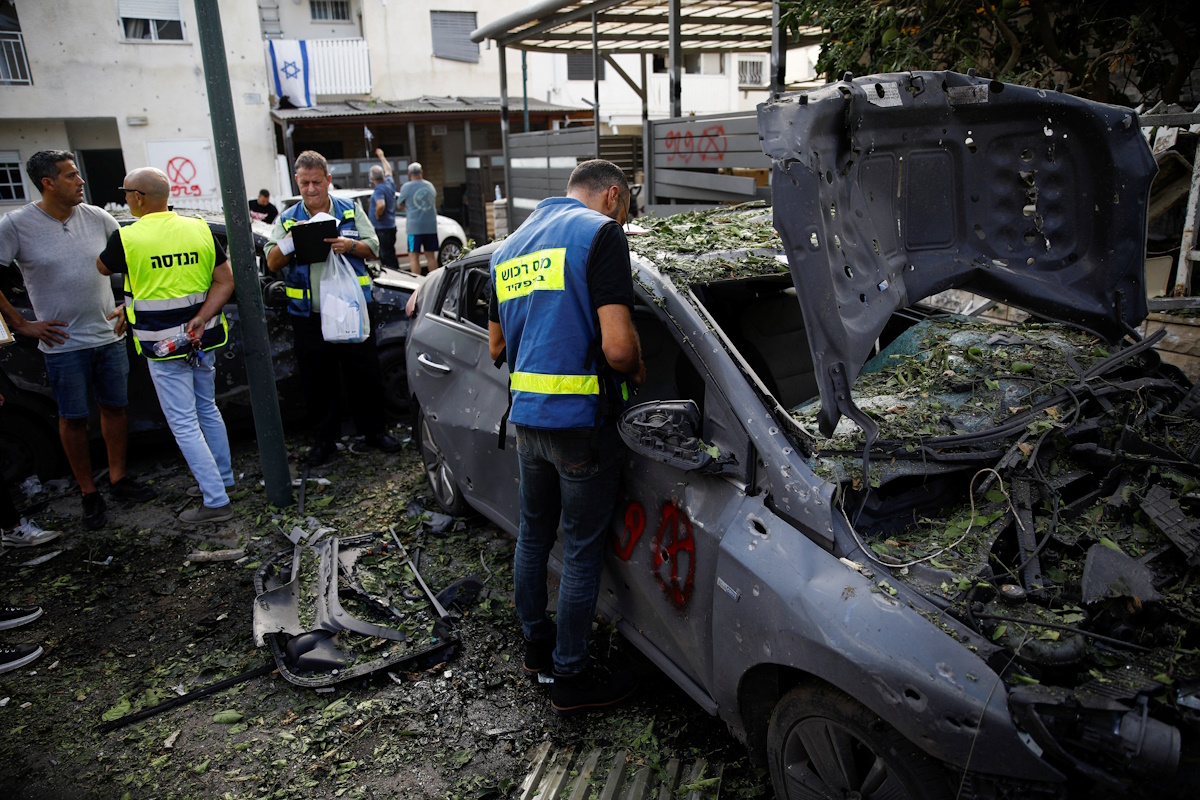 Emergency personnel work near damaged vehicles at a site of houses damaged following a rocket attack from Lebanon, amid cross-border hostilities between Hezbollah and Israel, in Kiryat Bialik, Israel, September 22, 2024. REUTERS