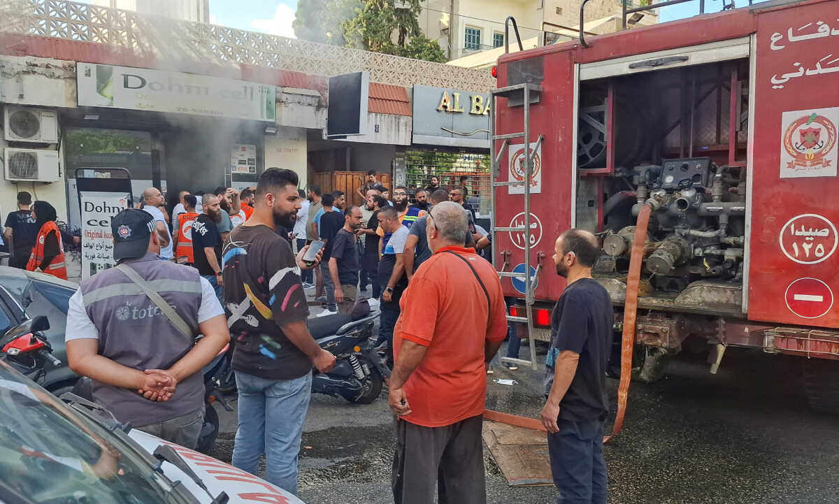 People gather as smoke rises from a mobile shop in Sidon, Lebanon September 18, 2024. REUTERS