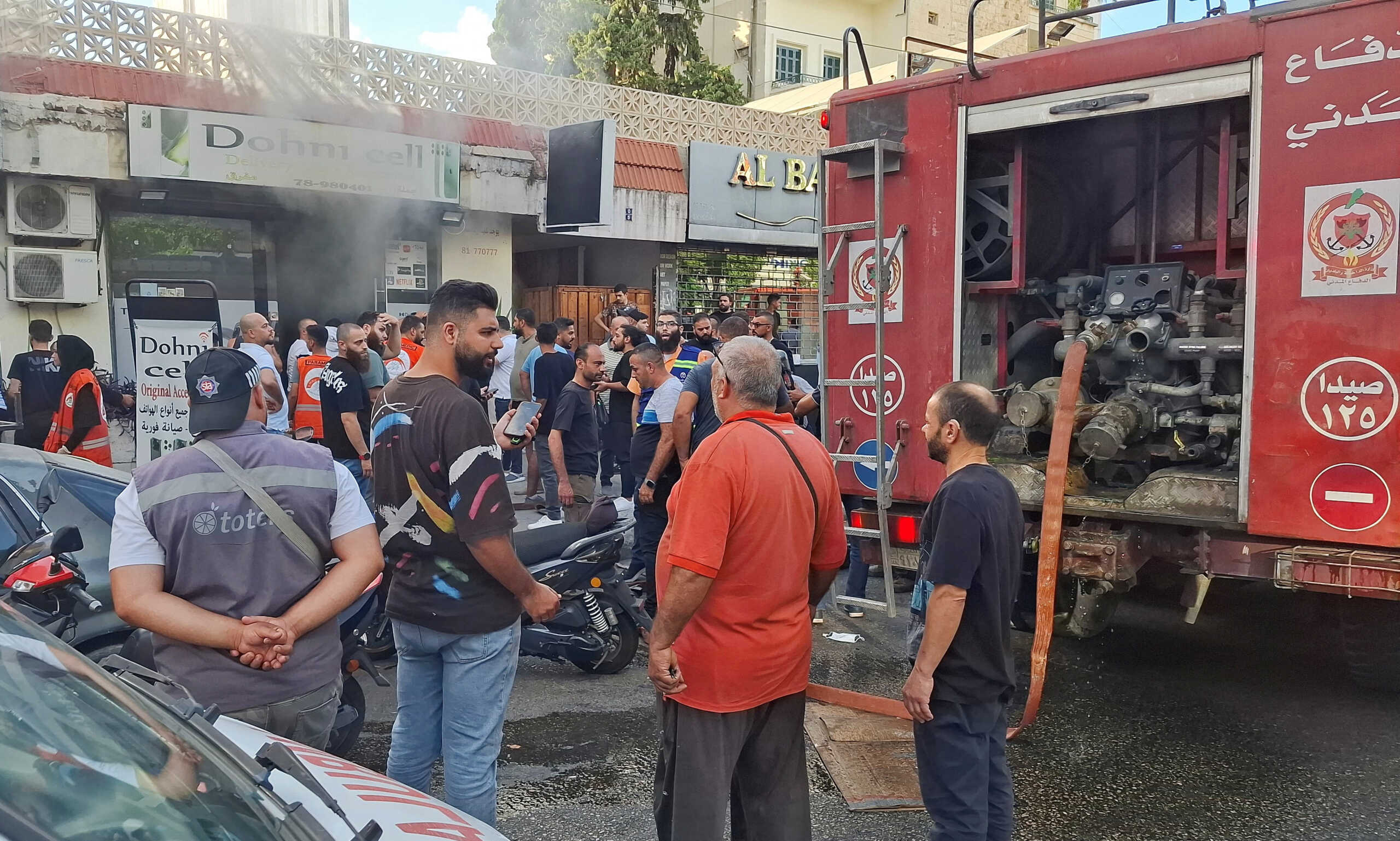 People gather as smoke rises from a mobile shop in Sidon, Lebanon September 18, 2024. REUTERS