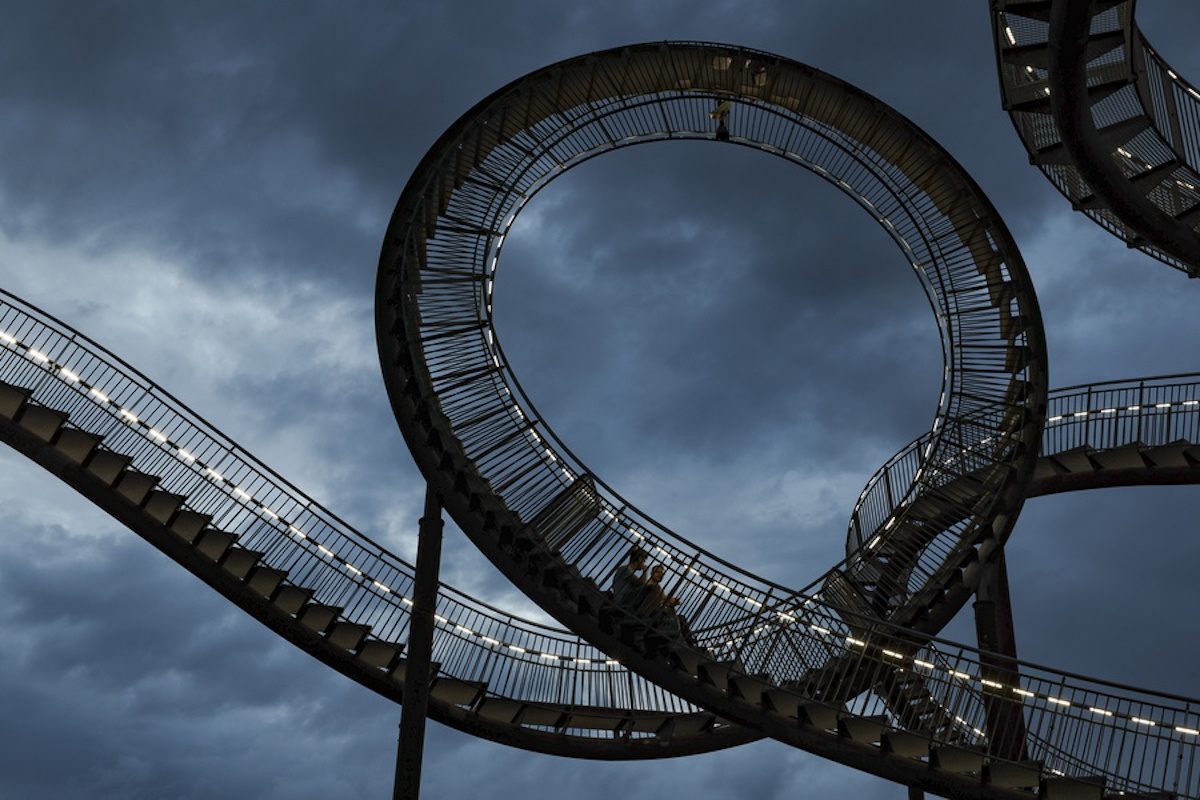 epa11582817 People sit on the large sculpture 'Tiger and Turtle - Magic Mountain' by German artists duo Heike Mutter and Ulrich Genth on a summer day in Duisburg, Germany, 03 September 2024. Tiger and Turtle - Magic Mountain is a large sculpture modelled on a roller coaster and is a work of art by Heike Mutter and Ulrich Genth that was developed as part of the Ruhr.2010 Capital of Culture.  EPA