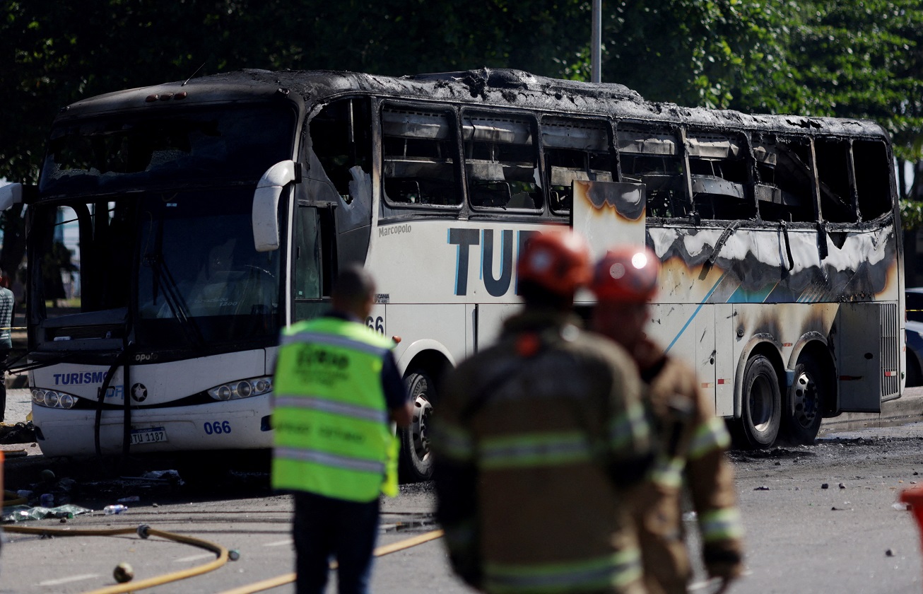 Soccer Football - Copa Libertadores - Semi Final - First leg - Botafogo v Penarol - Rio de Janeiro, Brazil - October 23, 2024 Firefighters are seen near a passenger bus after it was set on fire following incidents at Recreio dos Bandeirantes beach in which Penarol fans were detained REUTERS