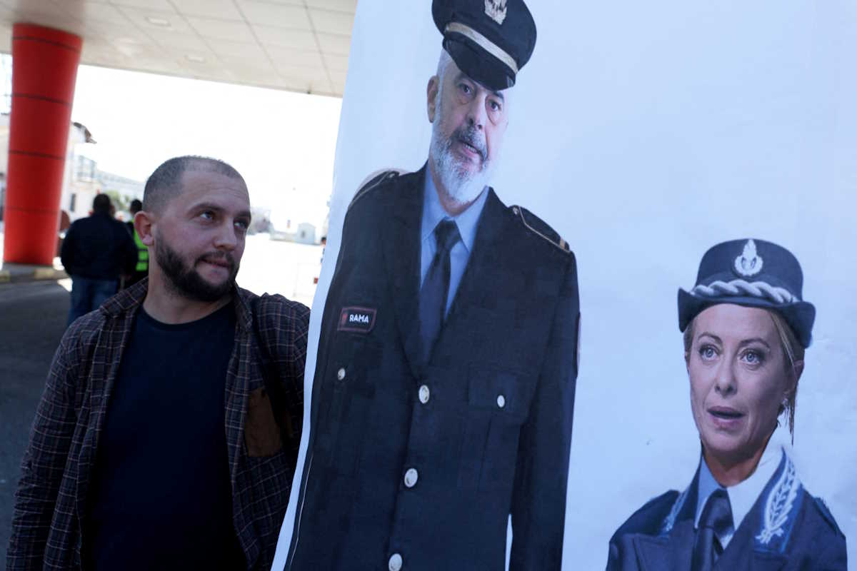 An activists holds a poster depicting Albanian Prime Minister Edi Rama and Italian Prime Minister Giorgia Meloni during a protest on the day migrants arrive on Italian navy ship Libra in Albania as part of a deal with Italy to process thousands of asylum-seekers caught near Italian waters, in Shengjin, Albania, October 16, 2024. REUTERS