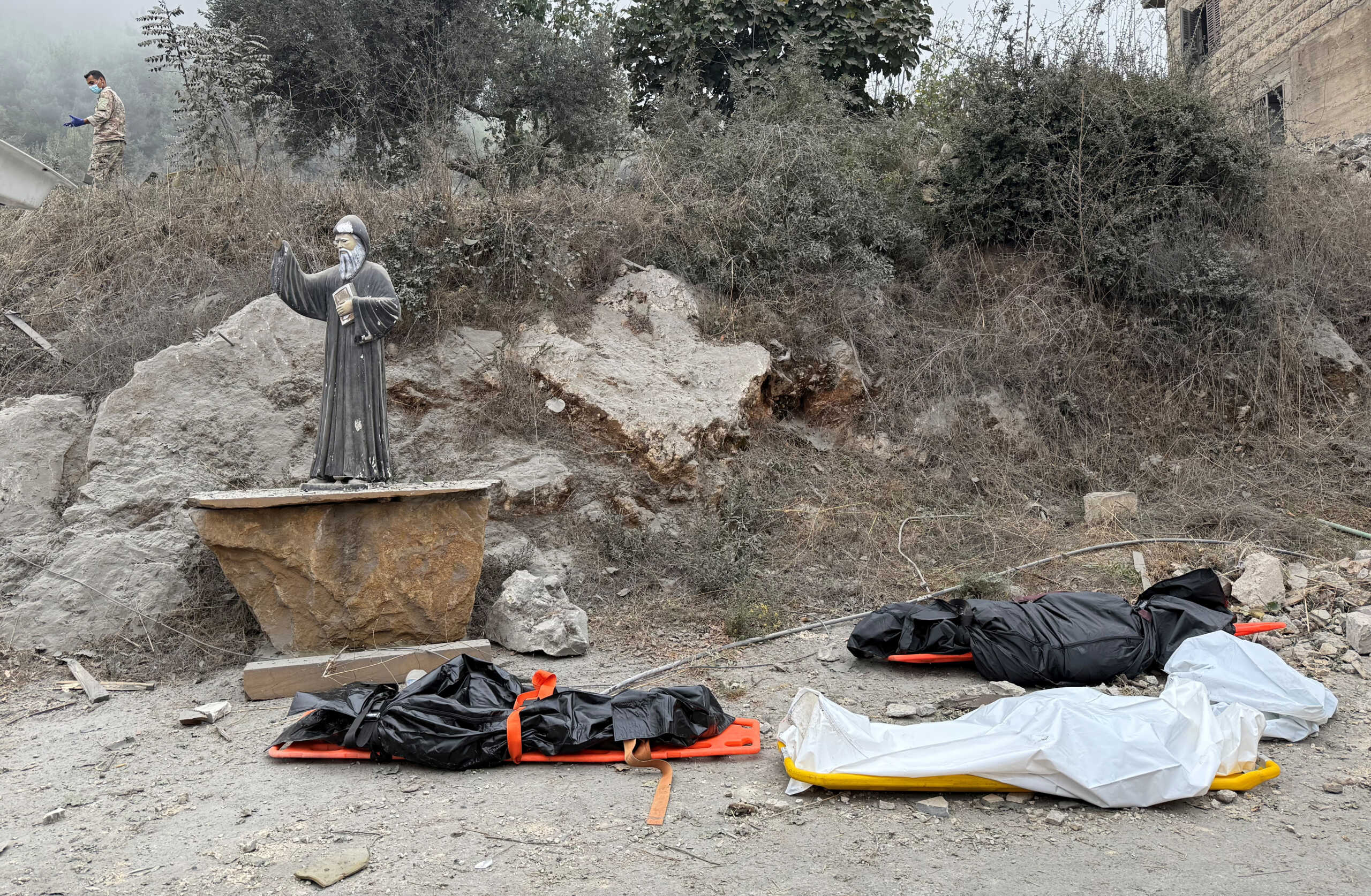 Dead bodies lie on the ground in bodybags near a statue of Saint Charbel, at a site of an Israeli air strike in the Christian-majority region of Aitou in north Lebanon, the Lebanese health ministry said, October 14, 2024. REUTERS