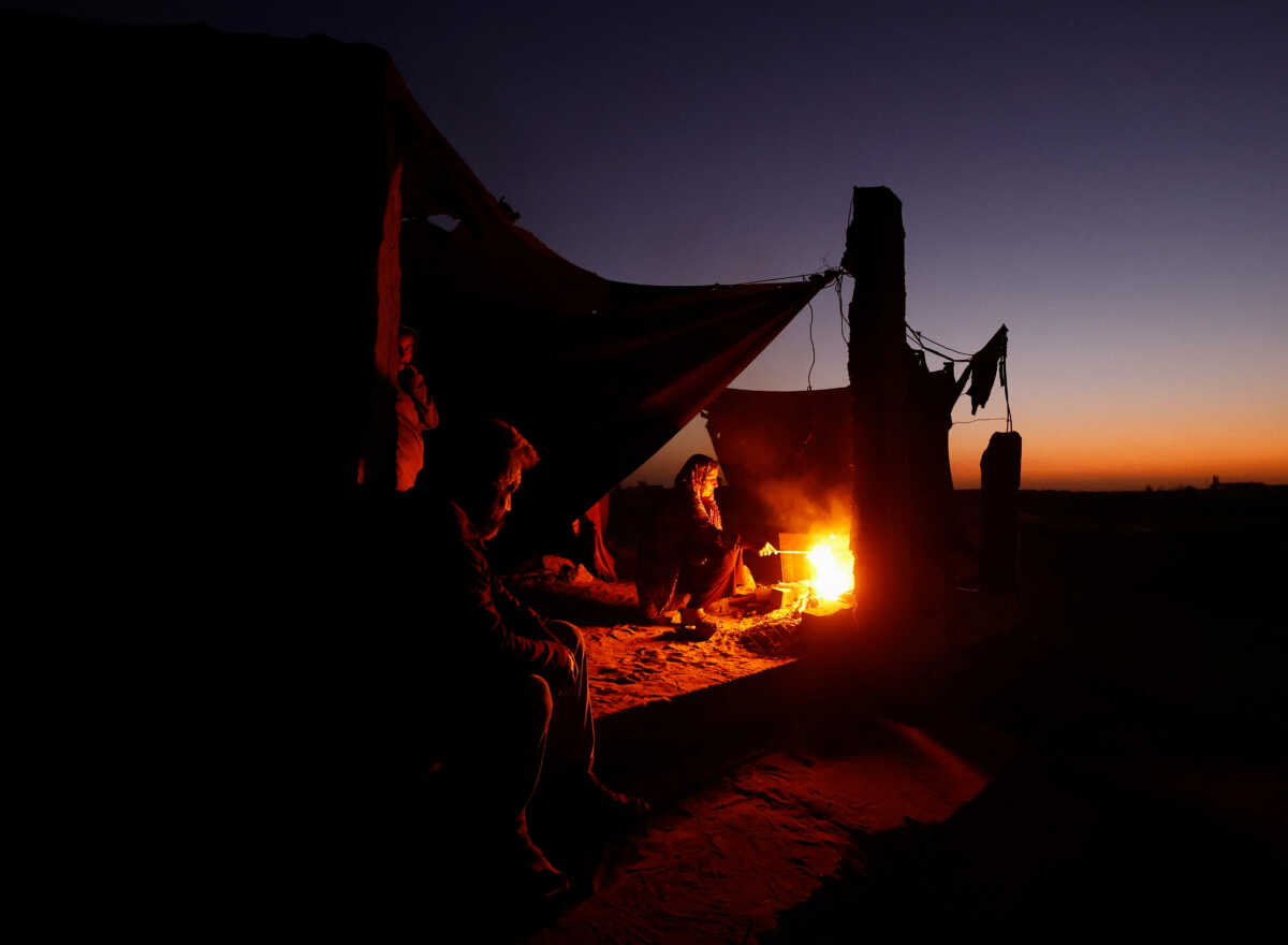 Displaced Palestinian light a fire next to their tent as they live at a cemetery, amid the Israel-Hamas conflict, in Khan Younis, in the southern Gaza Strip, October 27, 2024. REUTERS