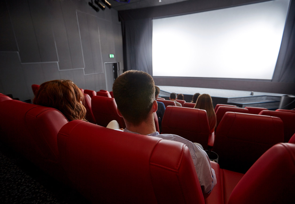 cinema, entertainment, leisure and people concept - couple watching movie in theater from back