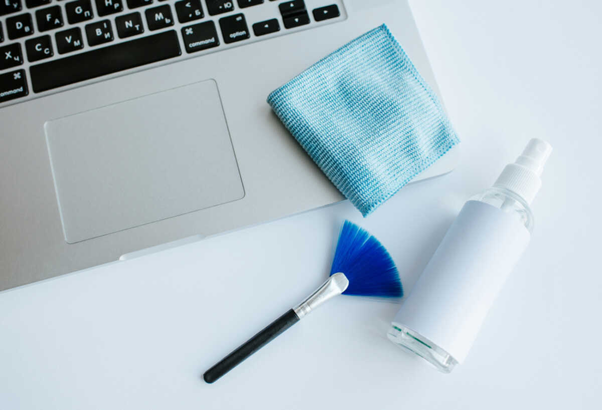 Laptop cleaning up. Service for cleaning notebook screen, keyboard, case. Cleaning accessories: brush, cloth, spray. Computer monitor, display care. Professional service, clean up. Man who wipe laptop