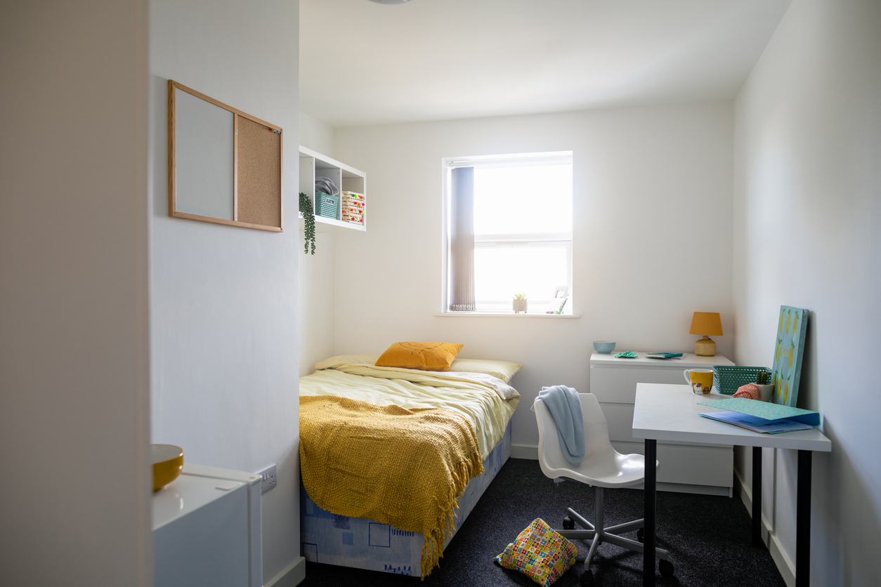 University bedroom in the North East of England. There is a single bed, a desk and no people.