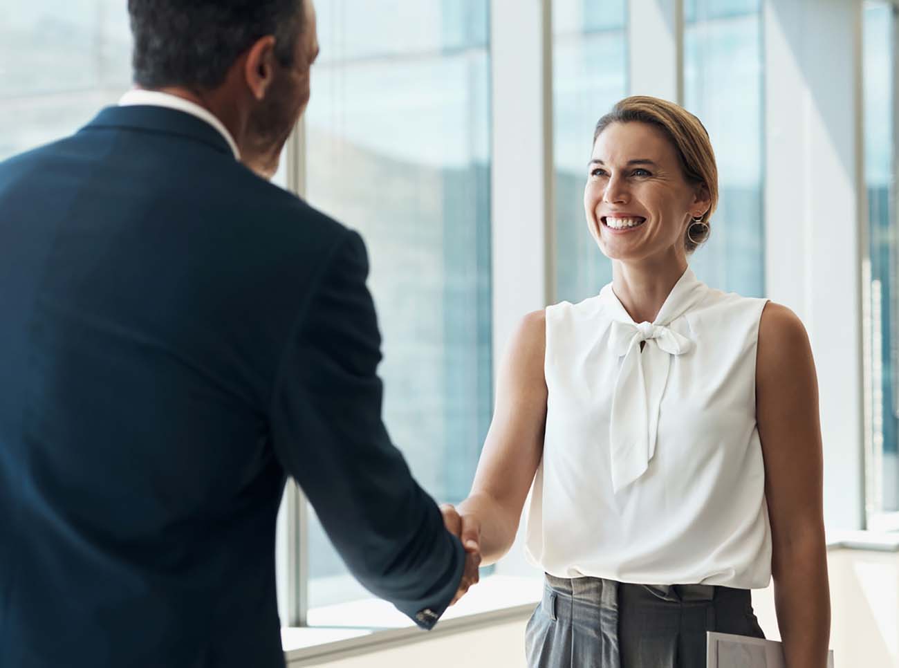 Handshake, meeting and business people partnership for b2b collaboration, onboarding welcome or professional opportunity. Corporate woman or clients shake hands for deal in office building interview