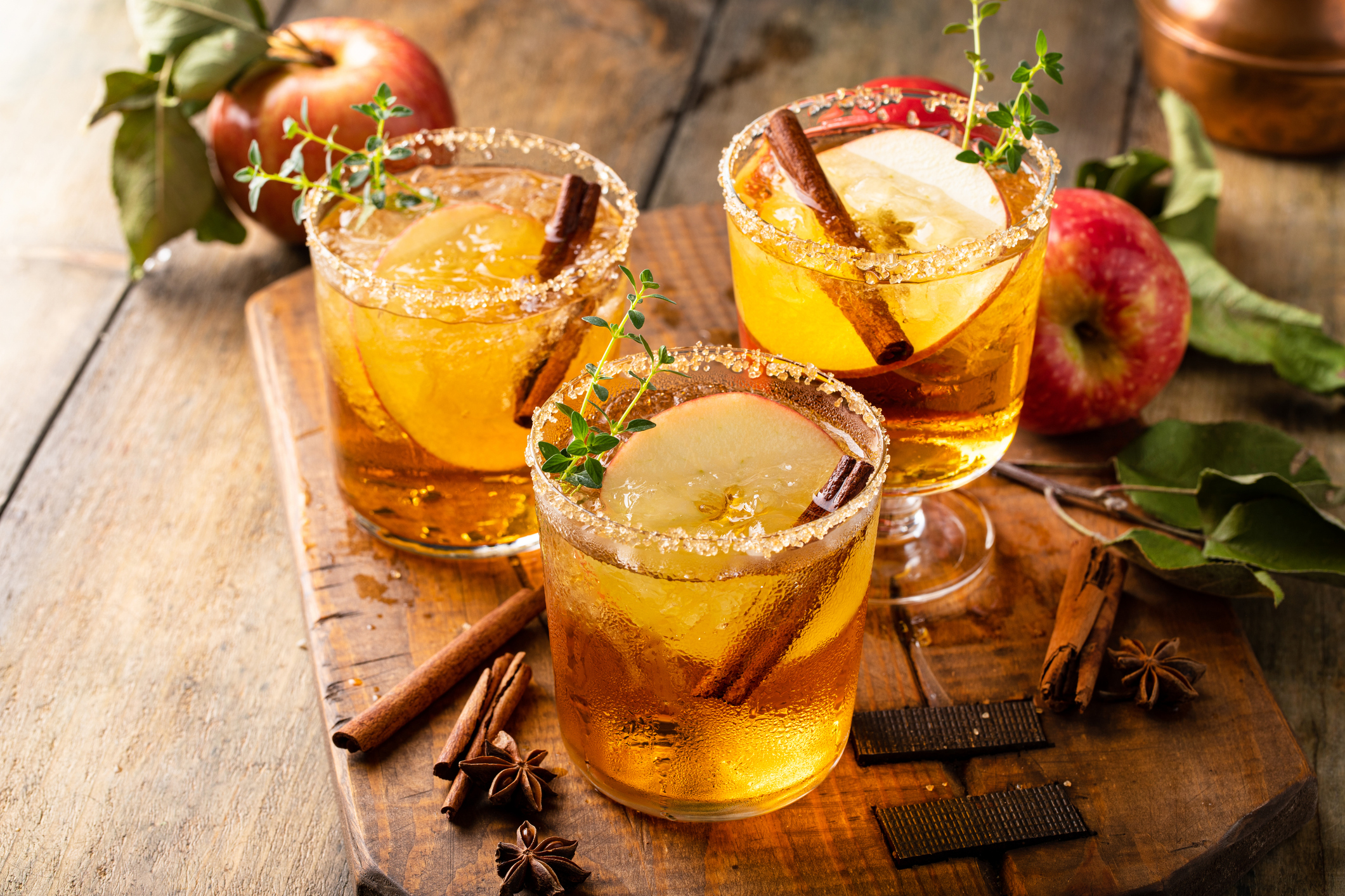 Apple cider margarita with brown sugar and spices on a rustic wooden surface, fall cocktail idea
