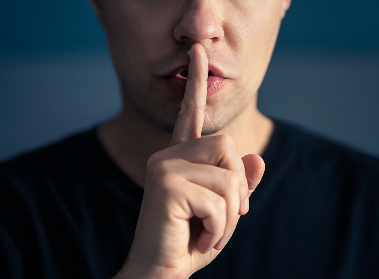 Secret and silence. Quiet silent shh gesture with finger on lips. Man doing expression with hand on mouth. Taboo topic, censorship or freedom or speech. Conspiracy theory. Confidential talk.