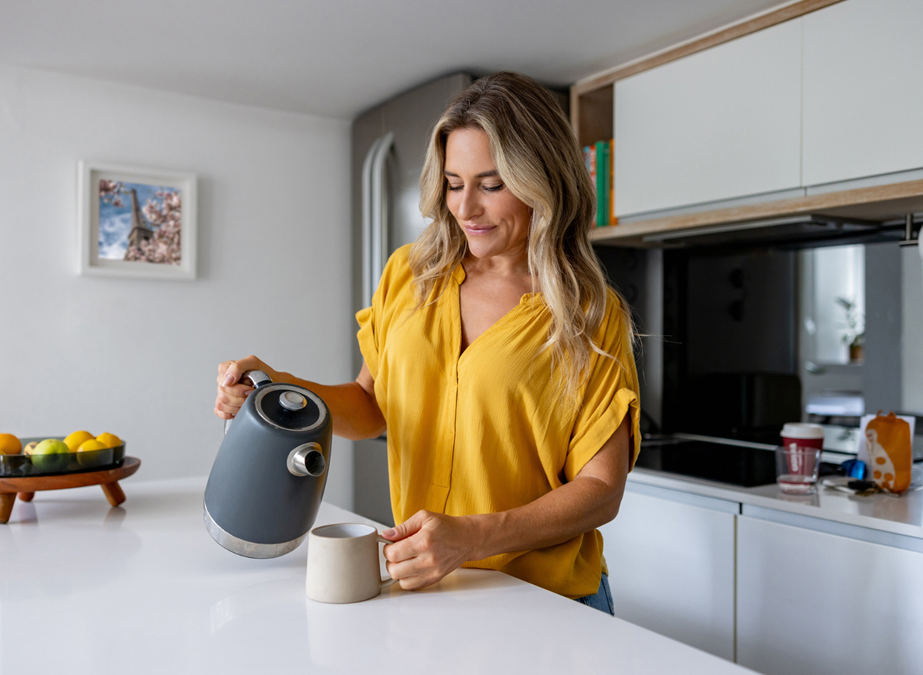 Happy woman at home making a cup of coffee in the kitchen and smiling -  morning routine concepts