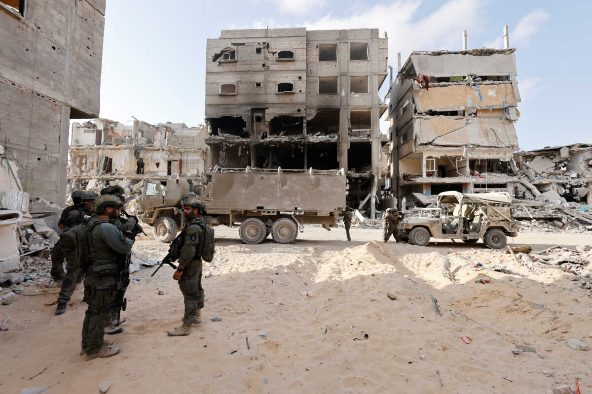 Israeli soldiers stand guard as damaged buildings are seen in the background, amid the ongoing ground operation of the Israeli army against Palestinian Islamist group Hamas, in the Gaza Strip, September 13, 2024. REUTERS